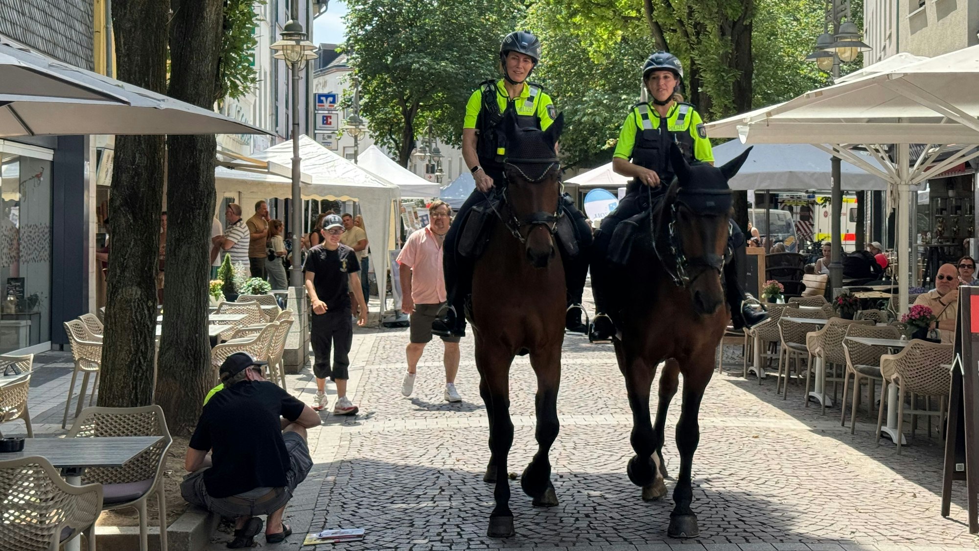 Zu sehen sind zwei Reiterinnen der Polizei auf ihre Pferden in der Brühler Fußgängerzone.
