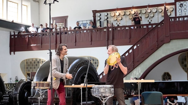 Zwei Männer stehen auf der Bühne, um sie herum Instrumente.