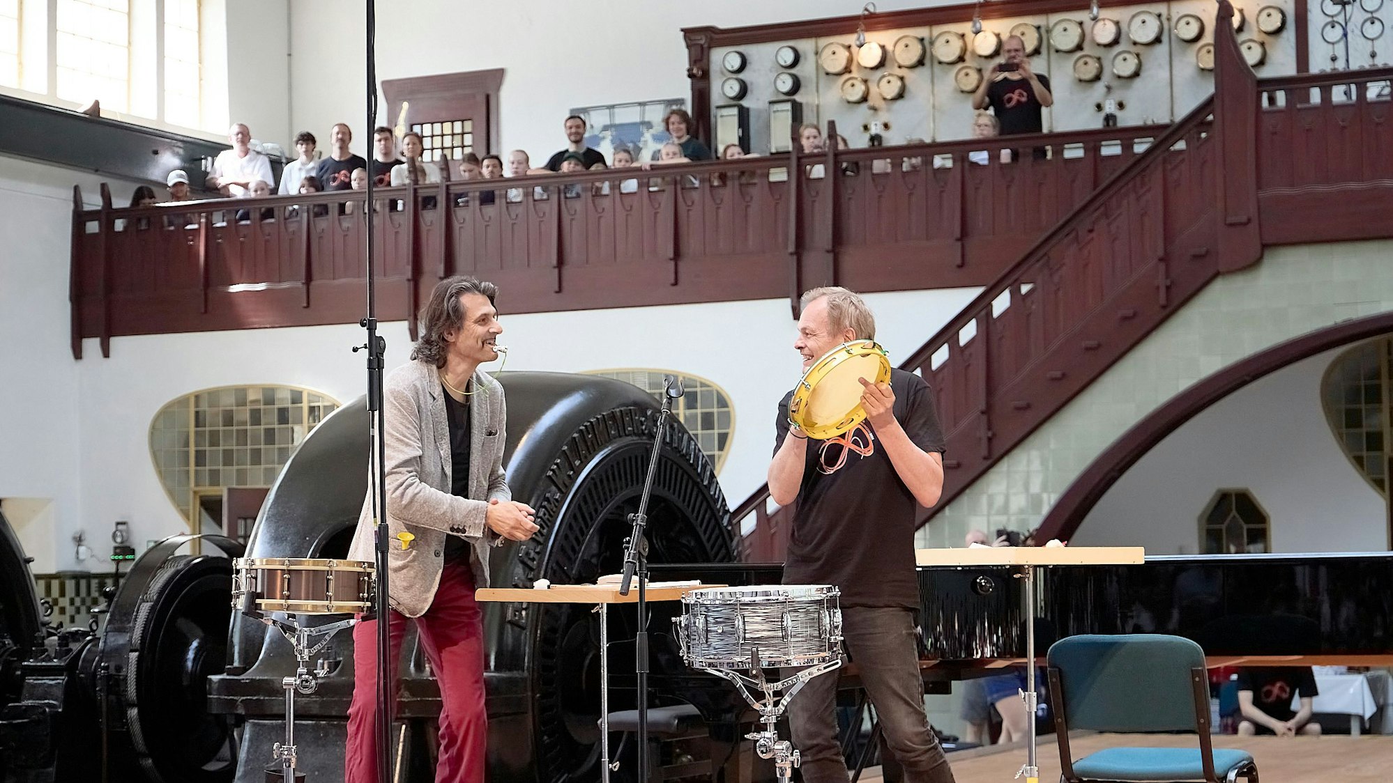 Zwei Männer stehen auf der Bühne, um sie herum Instrumente.