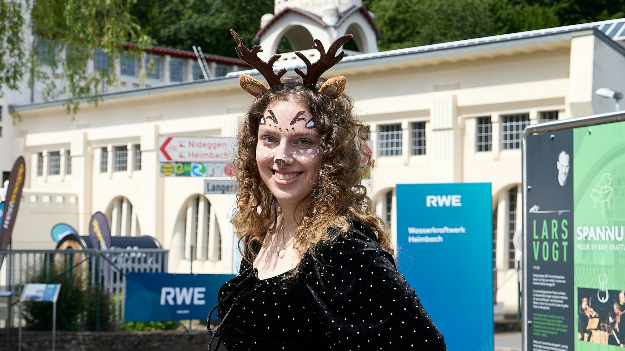 Isabelle Vogt, geschminkt und mit einem gebastelten Rentiergeweih auf dem Kopf, steht vor dem Kraftwerksgebäude in Heimbach.