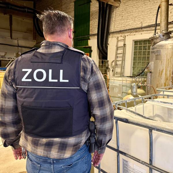 Das Bild zeigt einen Zollbeamten auf einer Hofanlage in Kerpen, wo illegal Drogen hergestellt wurden.