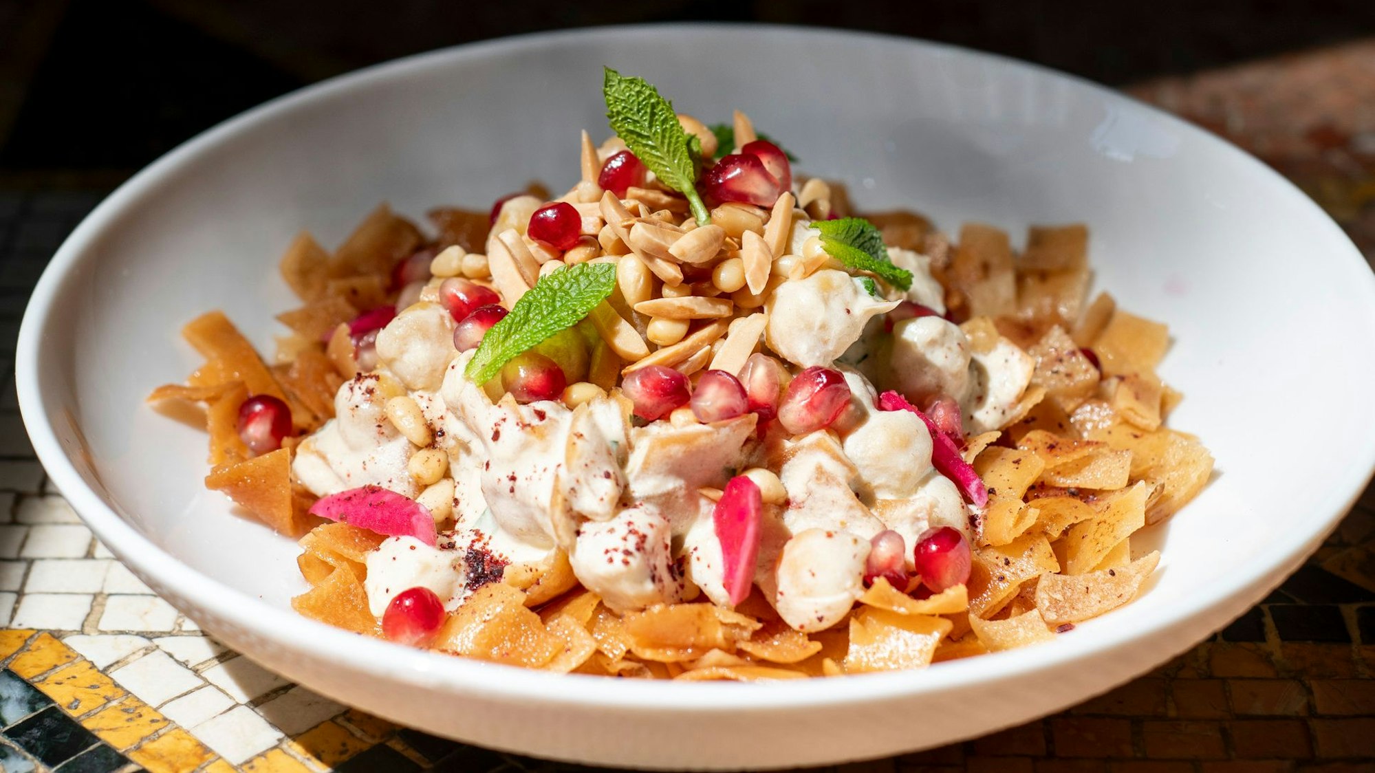 Hummus mit Brotchips, Joghurt und Pinienkernen.