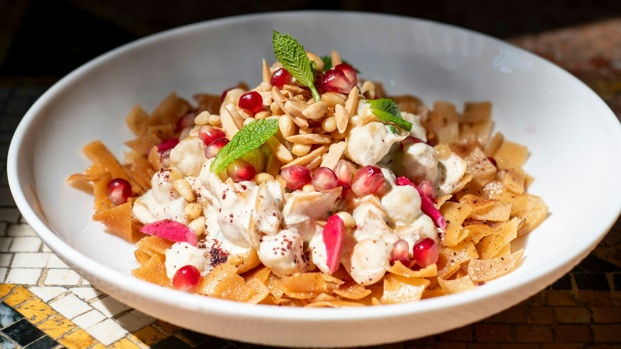 Hummus mit Brotchips, Joghurt und Pinienkernen.