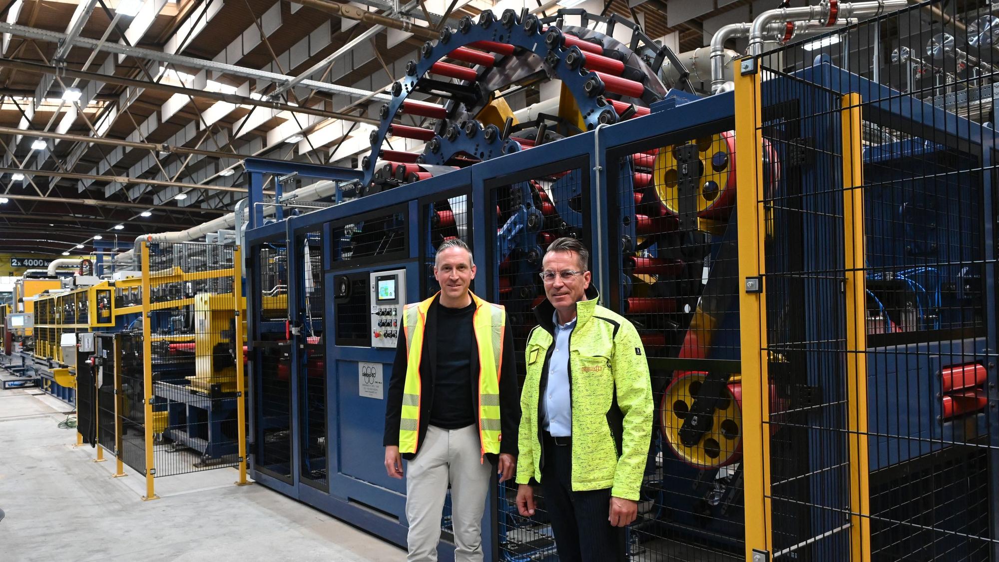 Die Geschäftsführer der Firma Schoeller, Alexander Mertens (l.) und Michael Gottschalk, stehen vor der insgesamt fast 100 Meter langen Laserschweißanlage, die in Hellenthal installiert wurde.