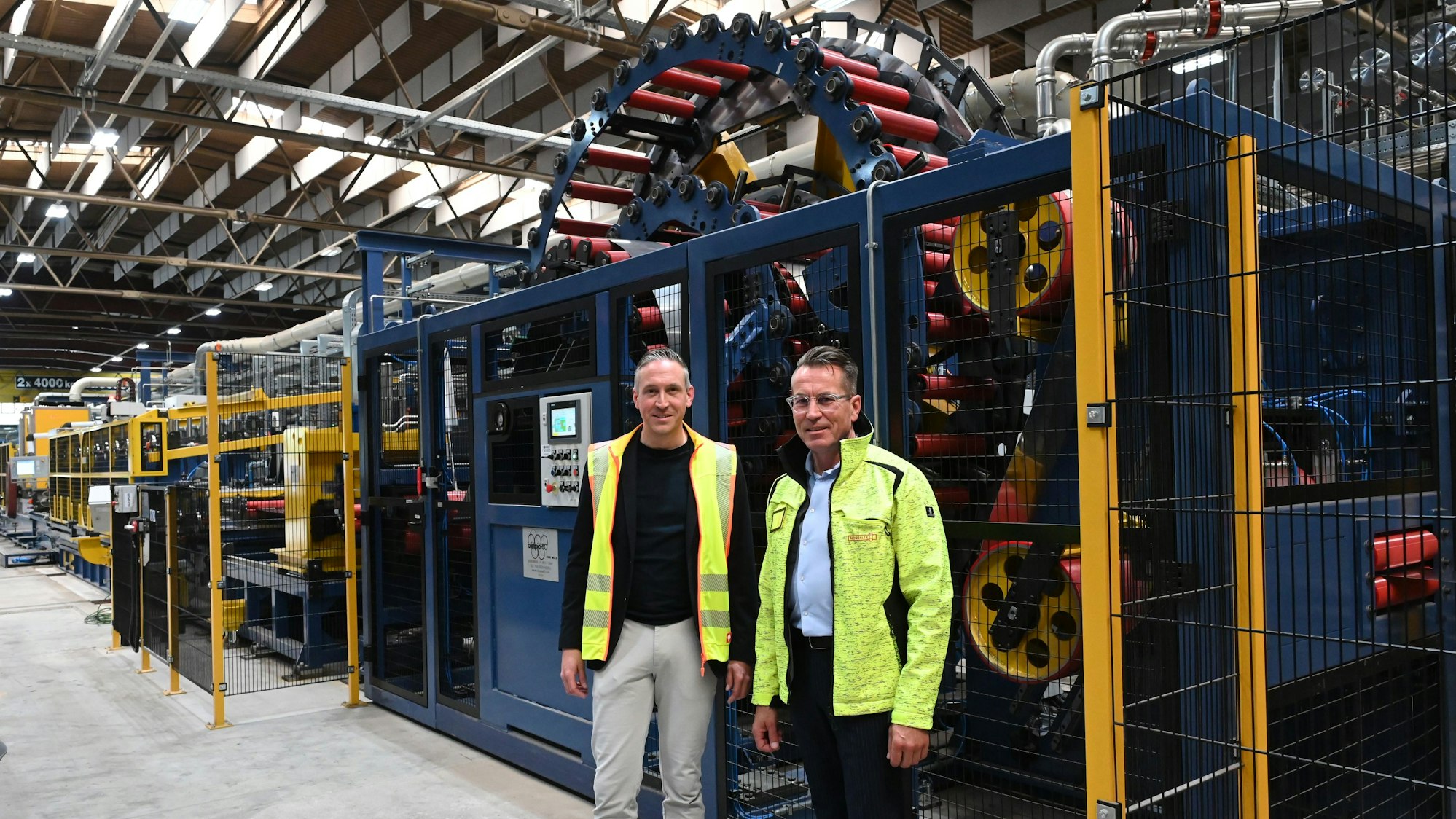 Die Geschäftsführer der Firma Schoeller, Alexander Mertens (l.) und Michael Gottschalk, stehen vor der insgesamt fast 100 Meter langen Laserschweißanlage, die in Hellenthal installiert wurde.