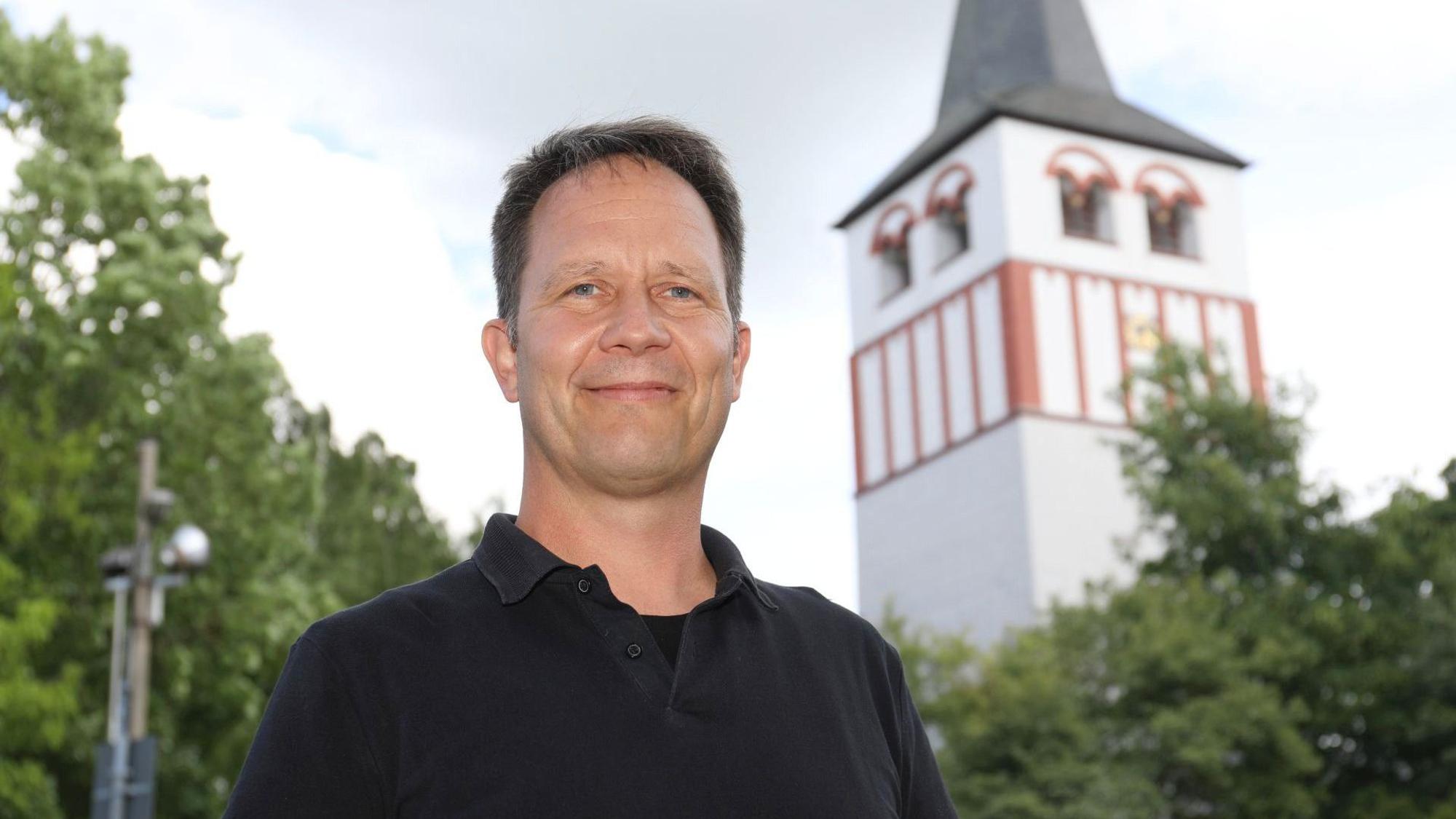 Ein Mann, im Hintergrund ein Kirchturm.