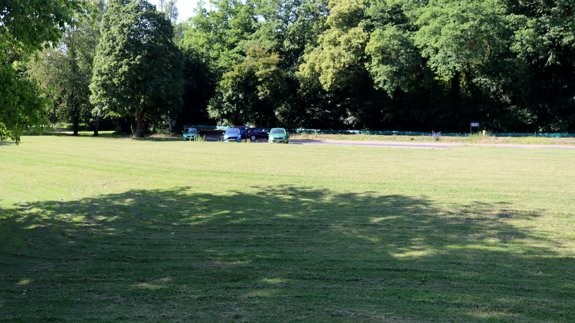 Ein Blick von einem kleinen Hügel in Richtung der Stelle, an der früher das Parkhotel in Bad Münstereifel stand. Auf der ehemaligen Einfahrt stehen Autos geparkt.