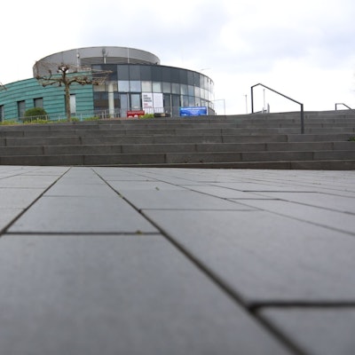 Ein Vorplatz und Treppenstufen vor einem ovalen Gebäude.