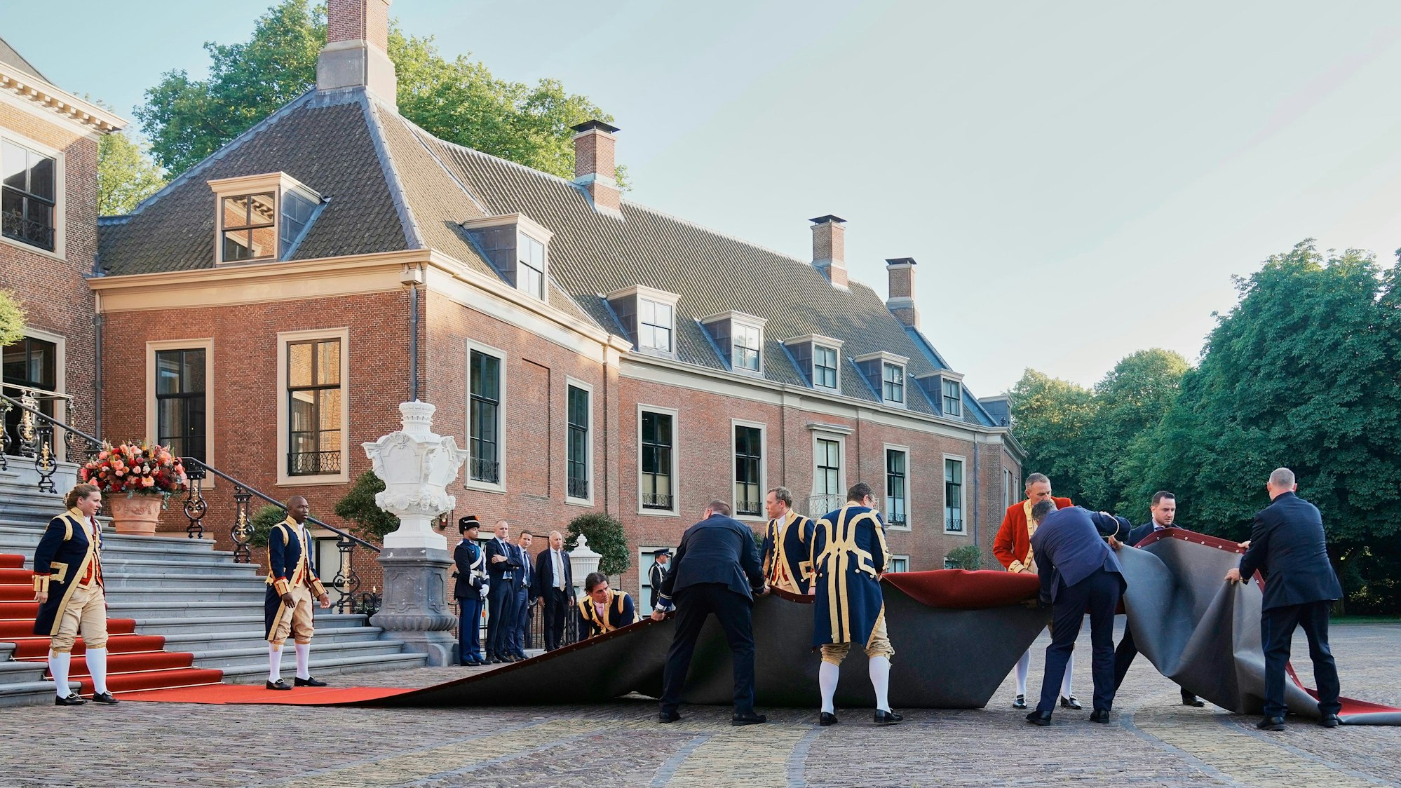 Mitarbeiter kümmern sich um den roten Teppich, der von einer Windböe weggeweht wurde.