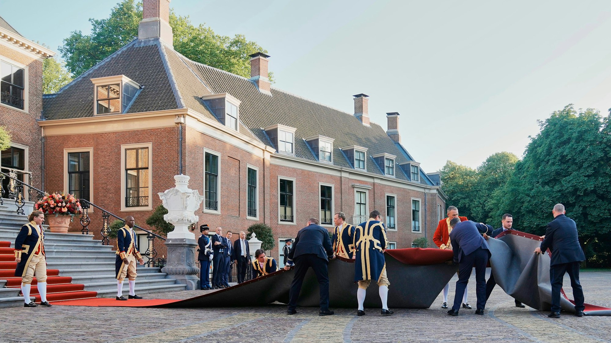 Mitarbeiter kümmern sich um den roten Teppich, der von einer Windböe weggeweht wurde.