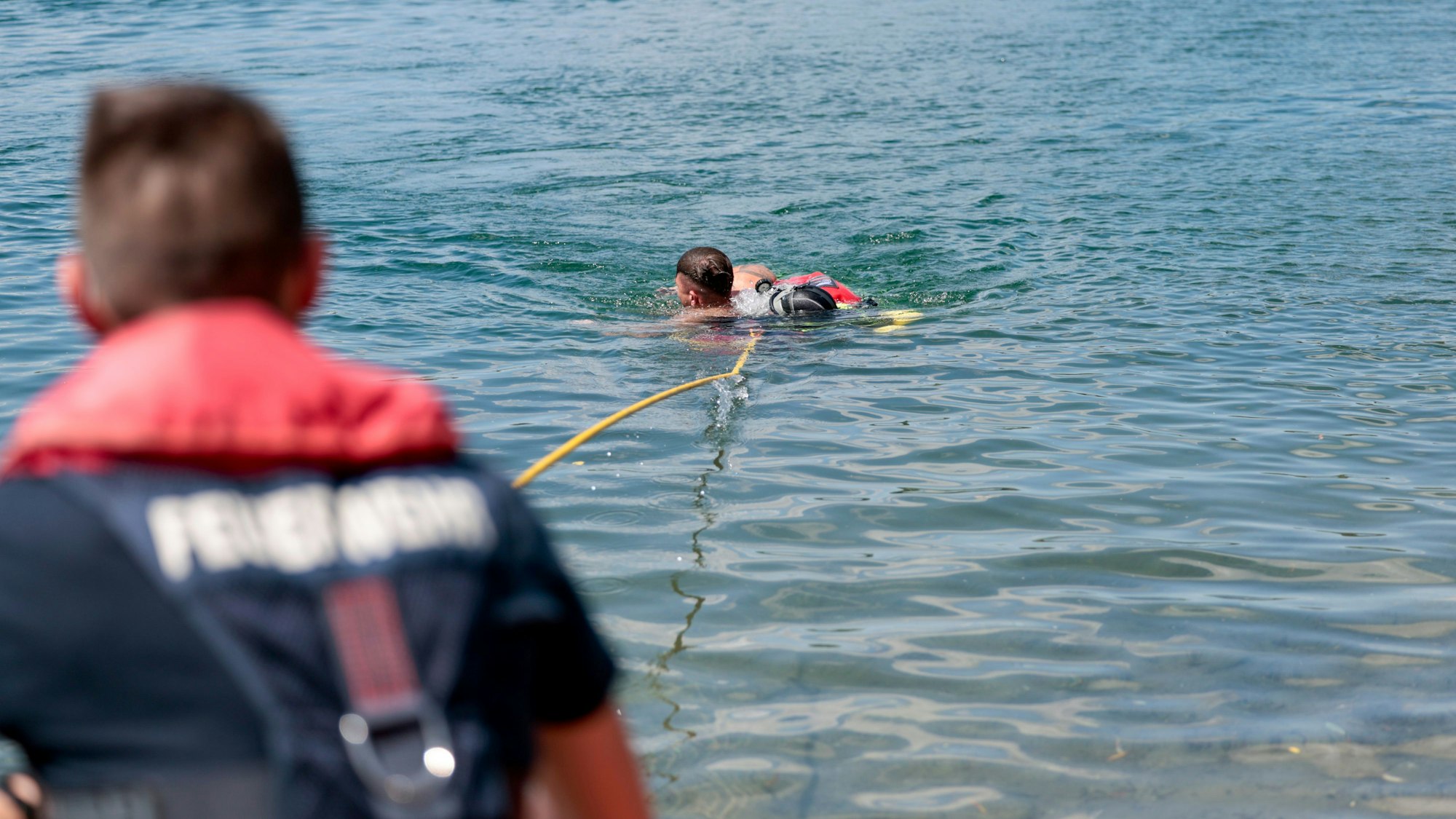 Taucher der Wasserrettung zeigen, wie sie eine Person aus dem Fühlinger See retten.
