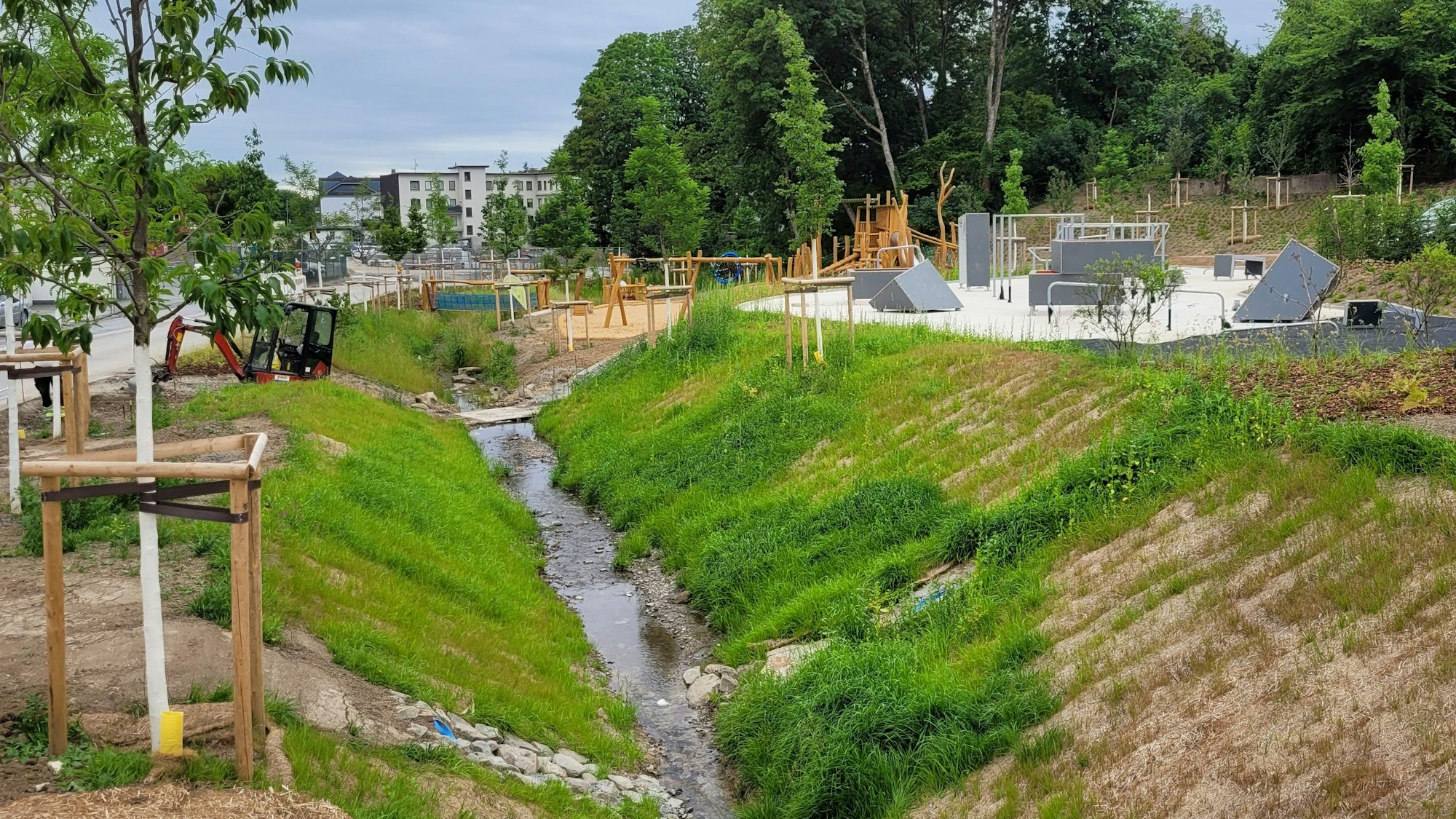 Freifließender Waldbrölbach, Parkour-Gelände (rechts) und Spielplatz: In Waldbröl gedieht auf dem früheren Merkur-Gelände der Grünzug-Ost. Die beiden Bewegungsgelände könnten schon im August freigegeben werden.