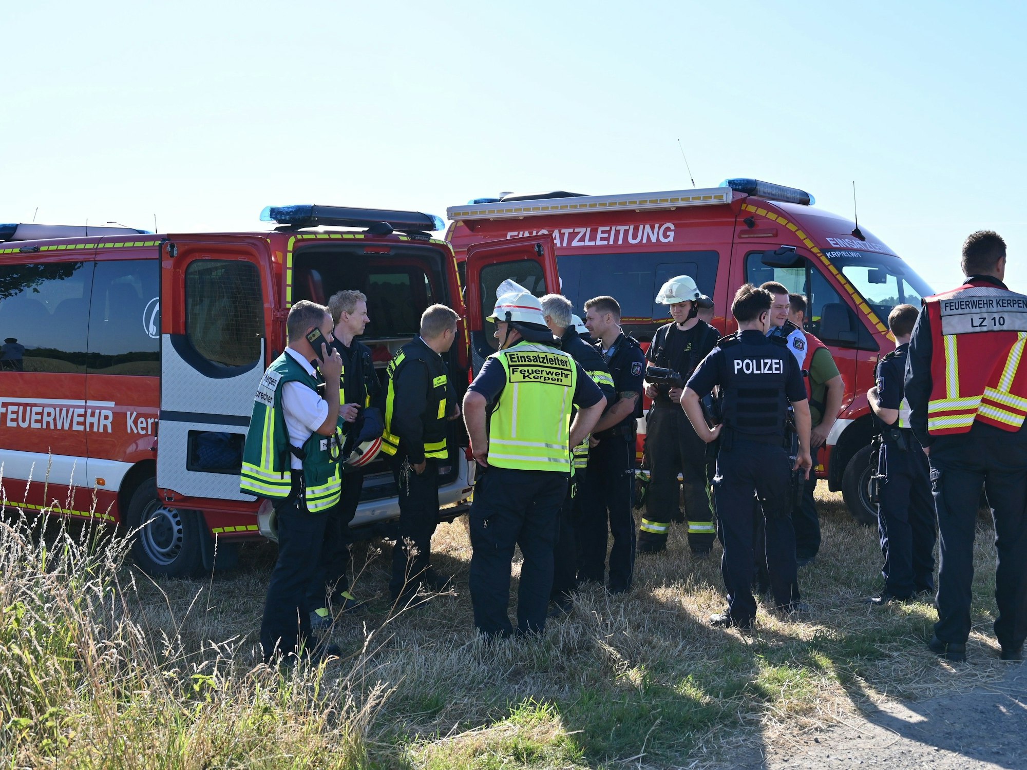 Das Bild zeigt mehrere Feuerwehrkräfte am Einsatzleitwagen.