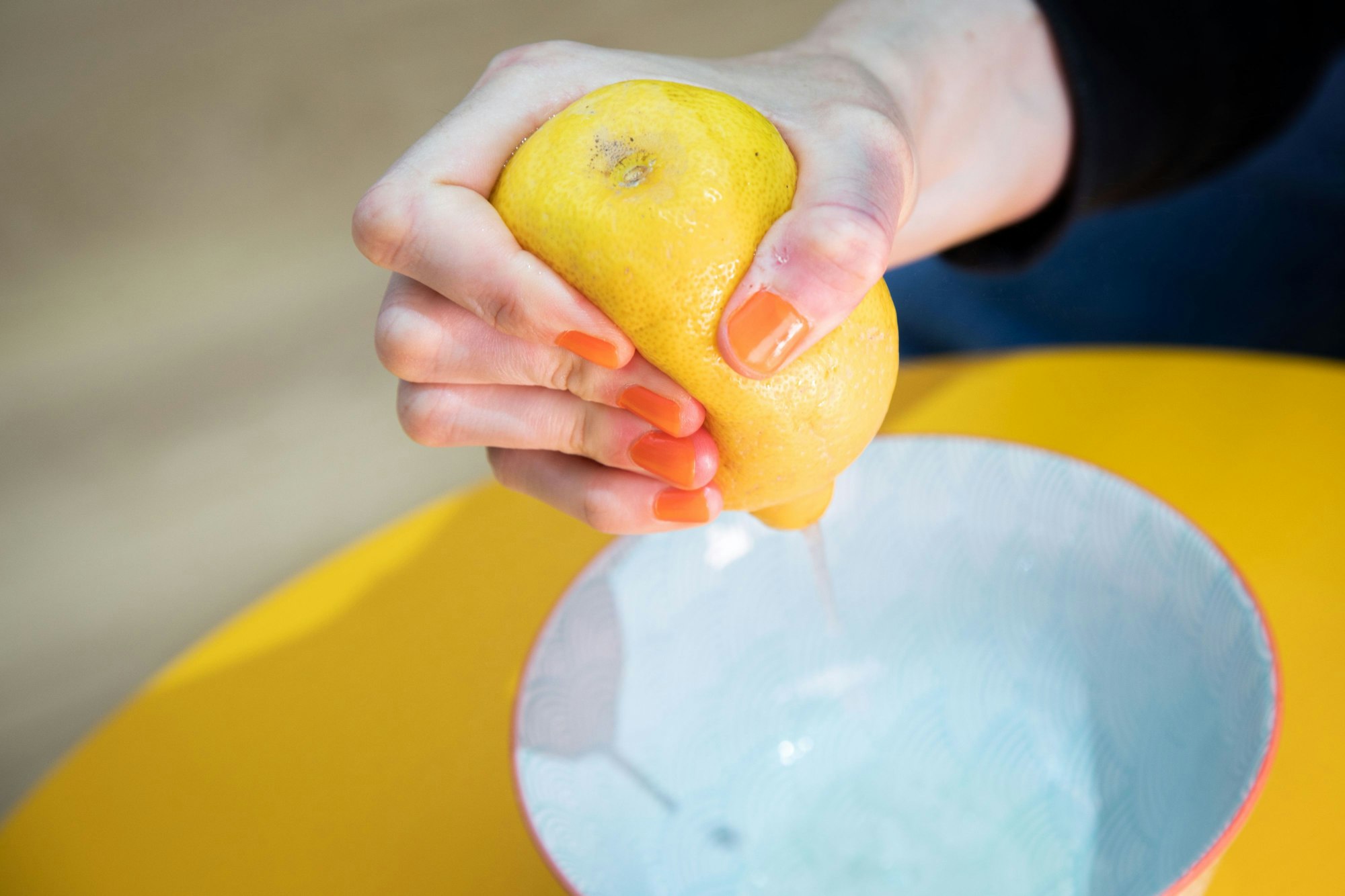 Schritt 2: Zitrone mit der Hand auspressen - der Saft spritzt kontrolliert in die Schale.