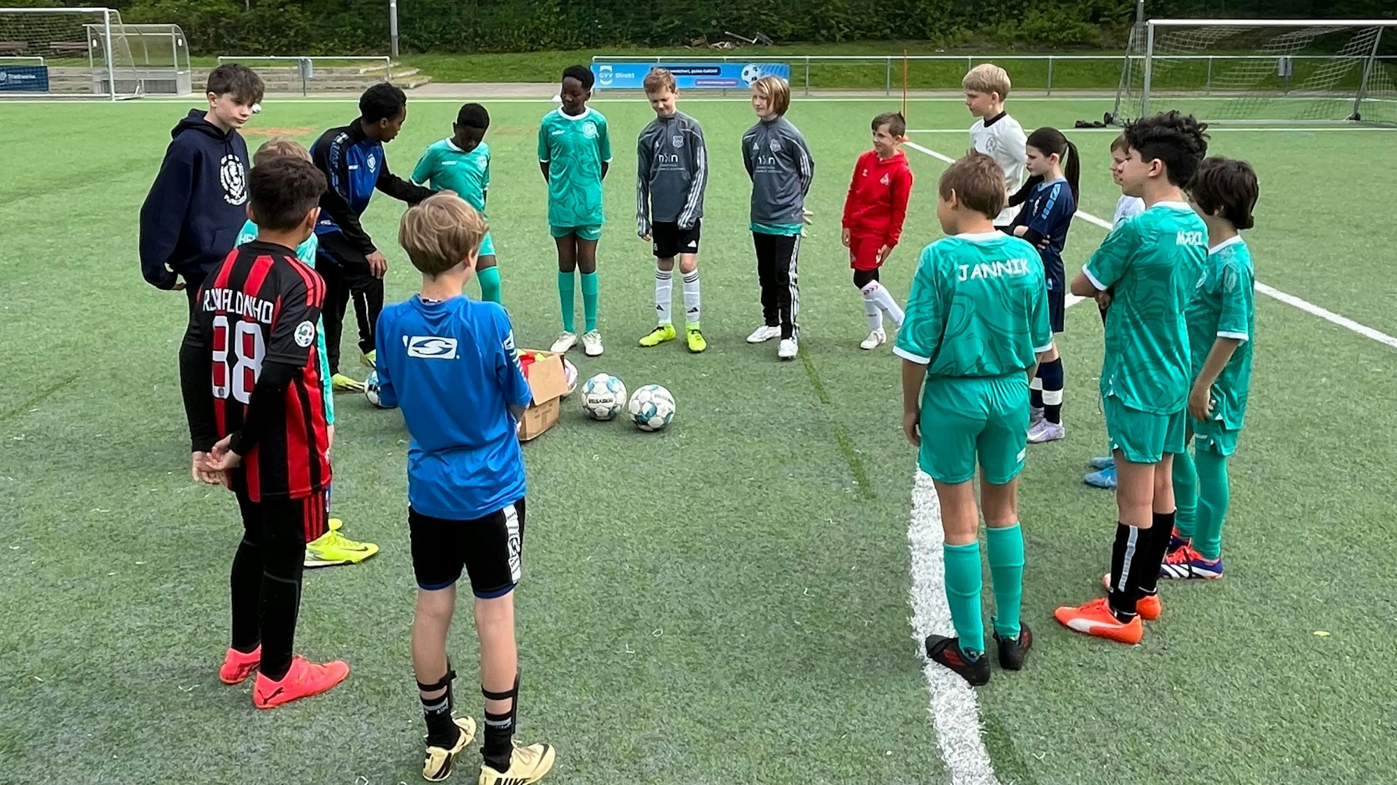 Zu sehen ist eine Gruppe junger Fußballer, die sich im Kreis versammelt haben.