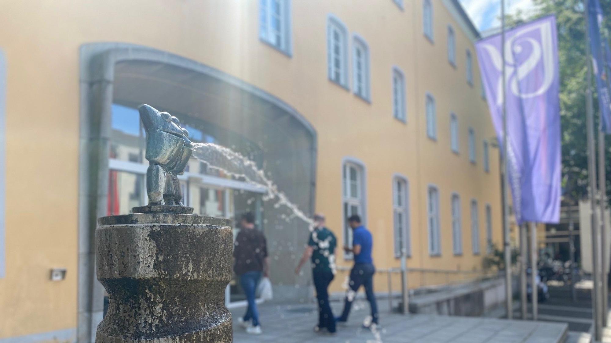 Zu sehen ist ein Brunnen und im Hintergrund der Eingang des Ratshauses.
