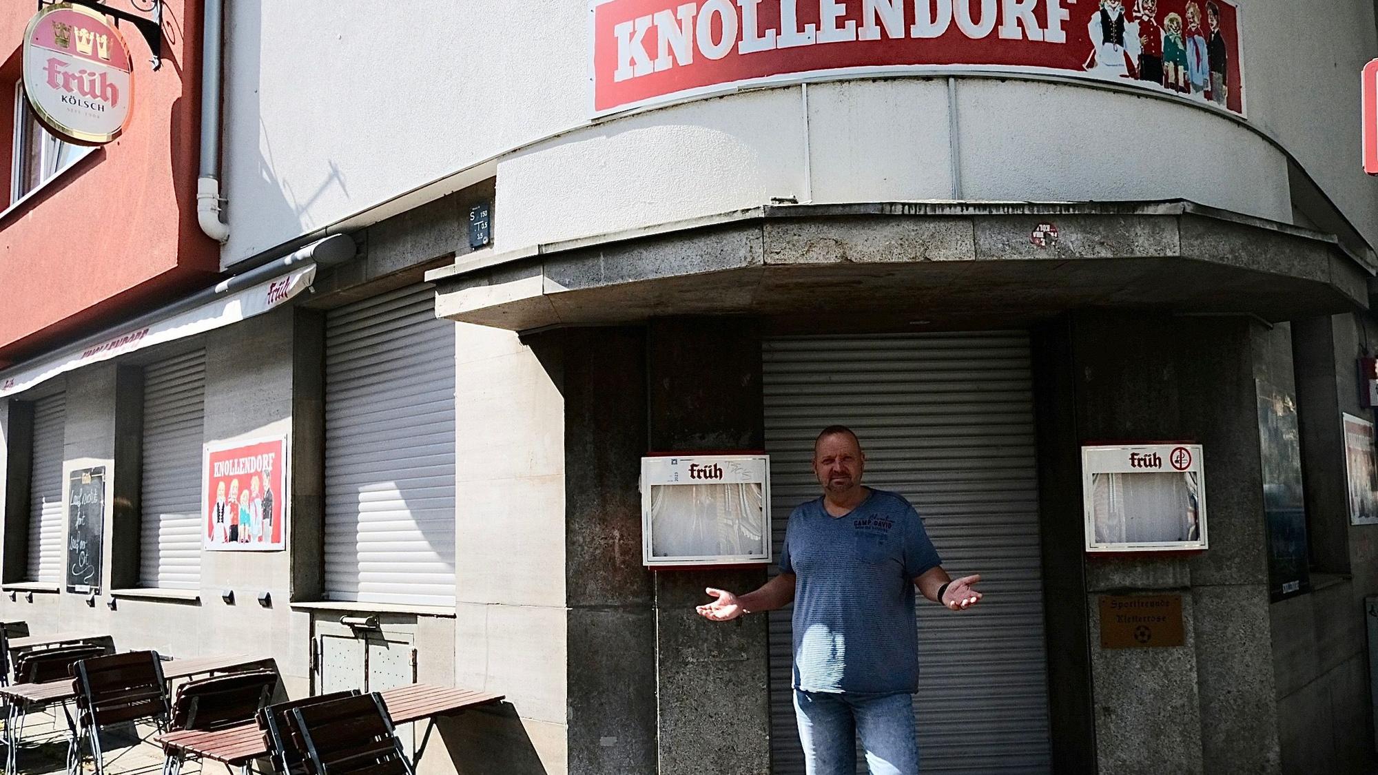 Ein Mann steht mit gehobenem Armen vor der geschlossenen Eingangstür seines Lokals Knollendorf.