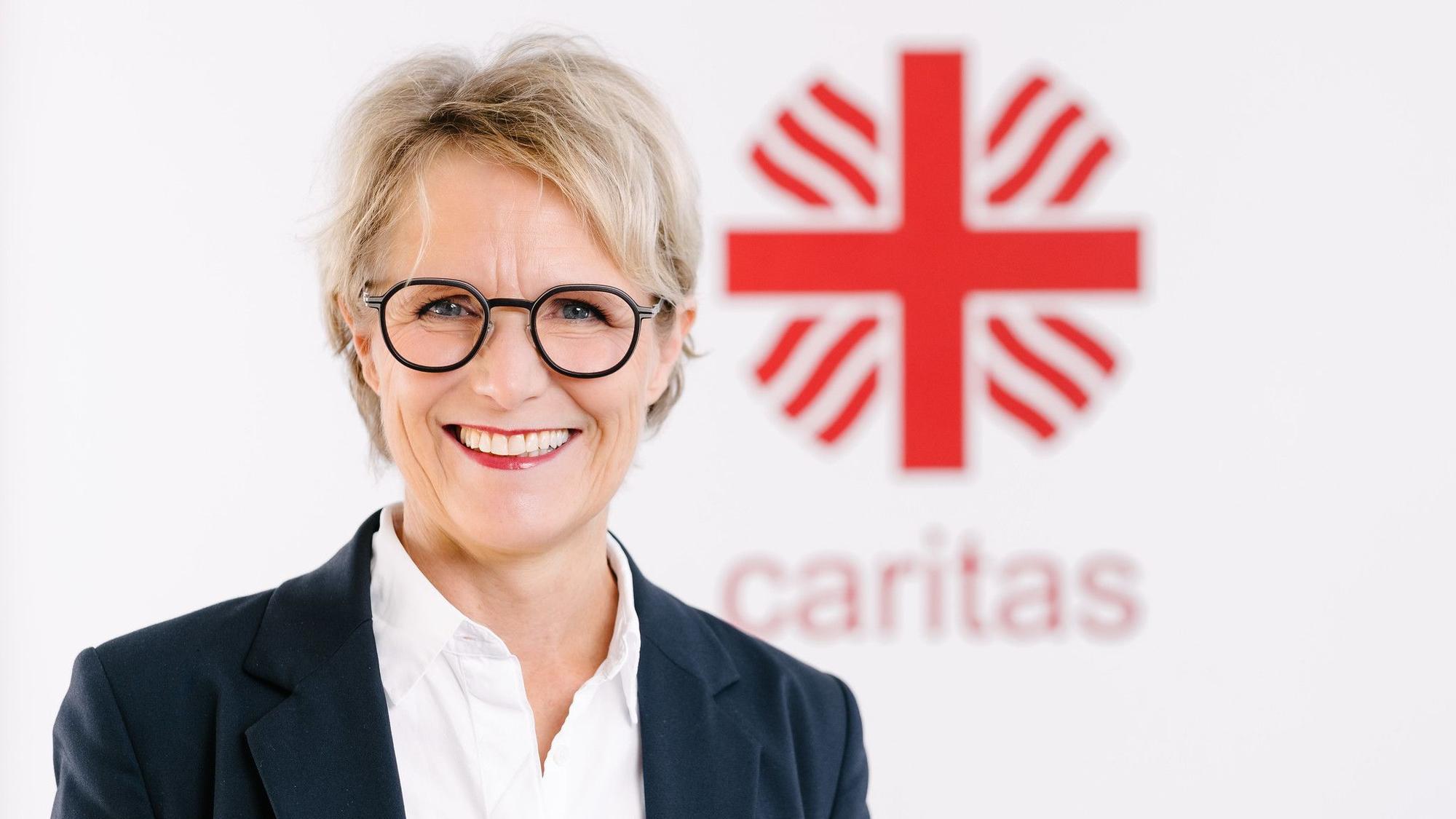 Das Foto zeigt die Finanzvorständin vor dem Caritas-Logo.