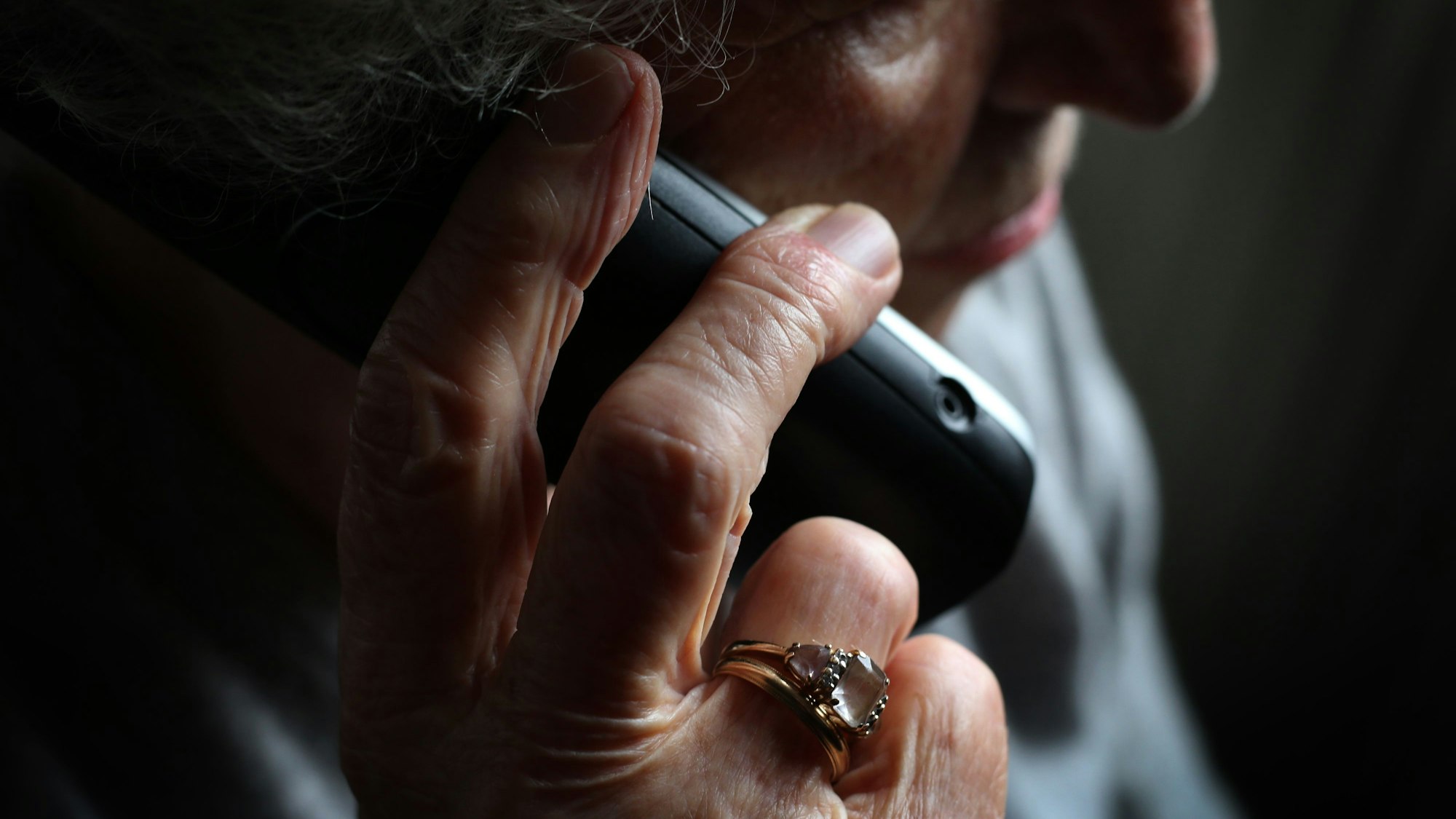 Eine ältere Frau hält sich einen Telefonhörer ans Ohr.