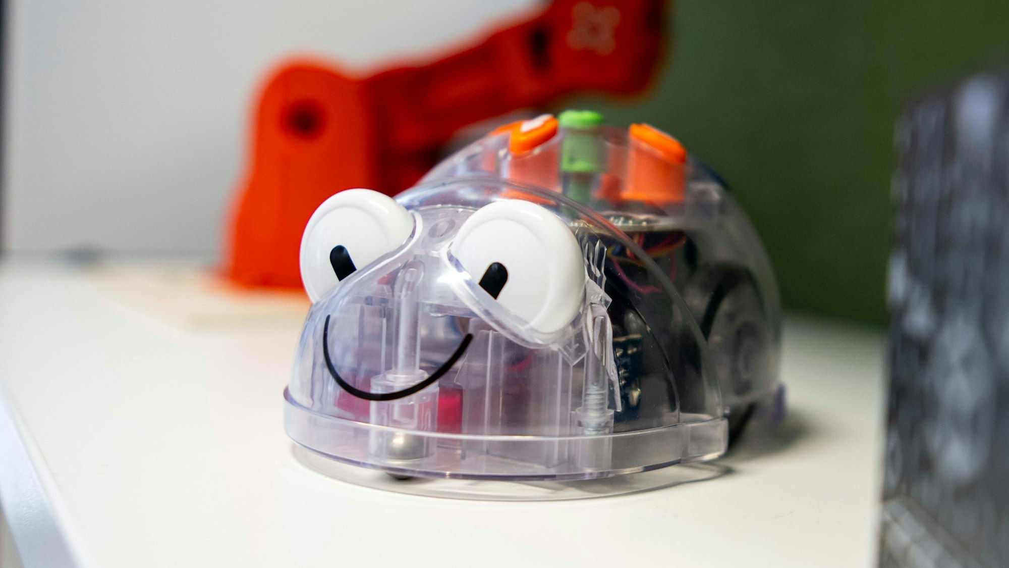 Das Bild zeigt einen kleinen Roboter, der von Grundschülern programmiert werden kann. Er hat auch Augen und einen aufgedruckten Mund.