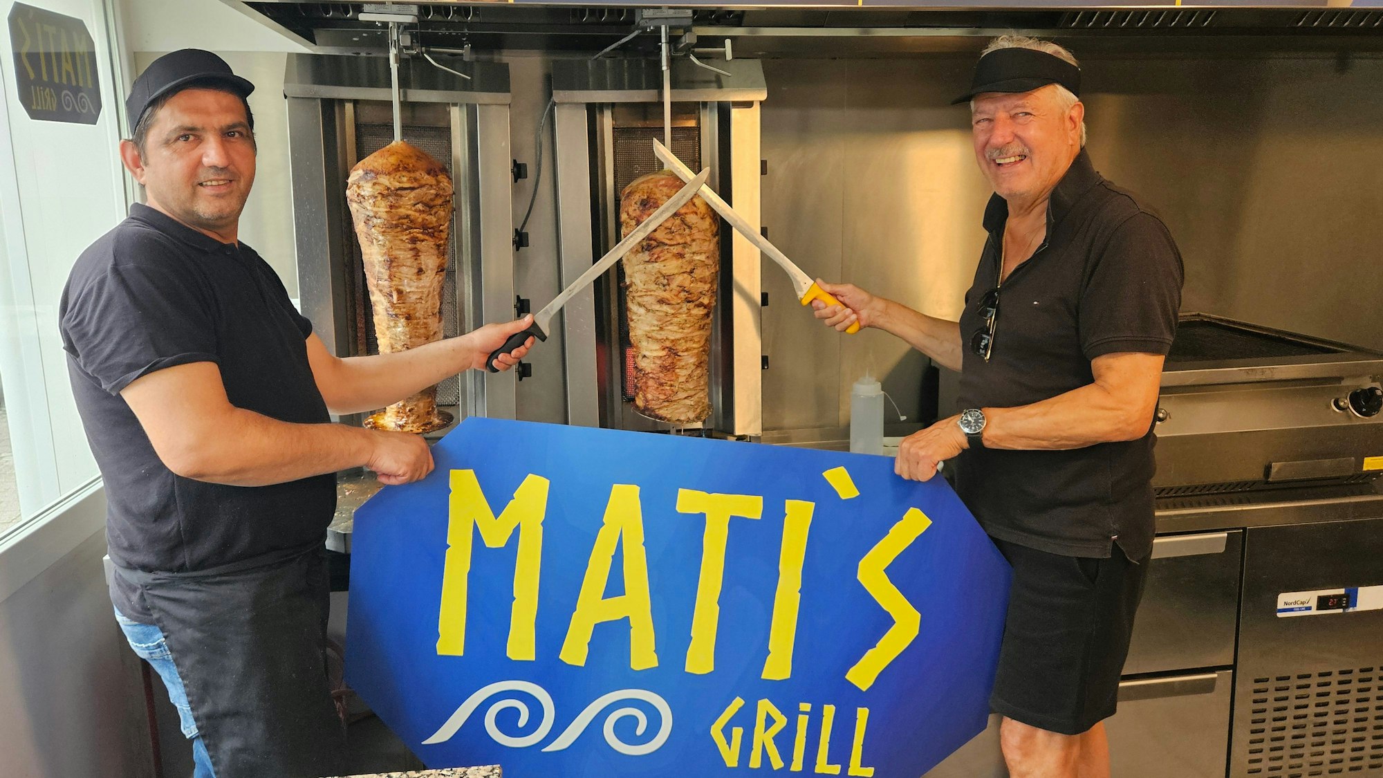 Zu sehen sind Agron Palamani und sein Vermieter Rolf Dieffendahl vor einem Gyrosgrill.