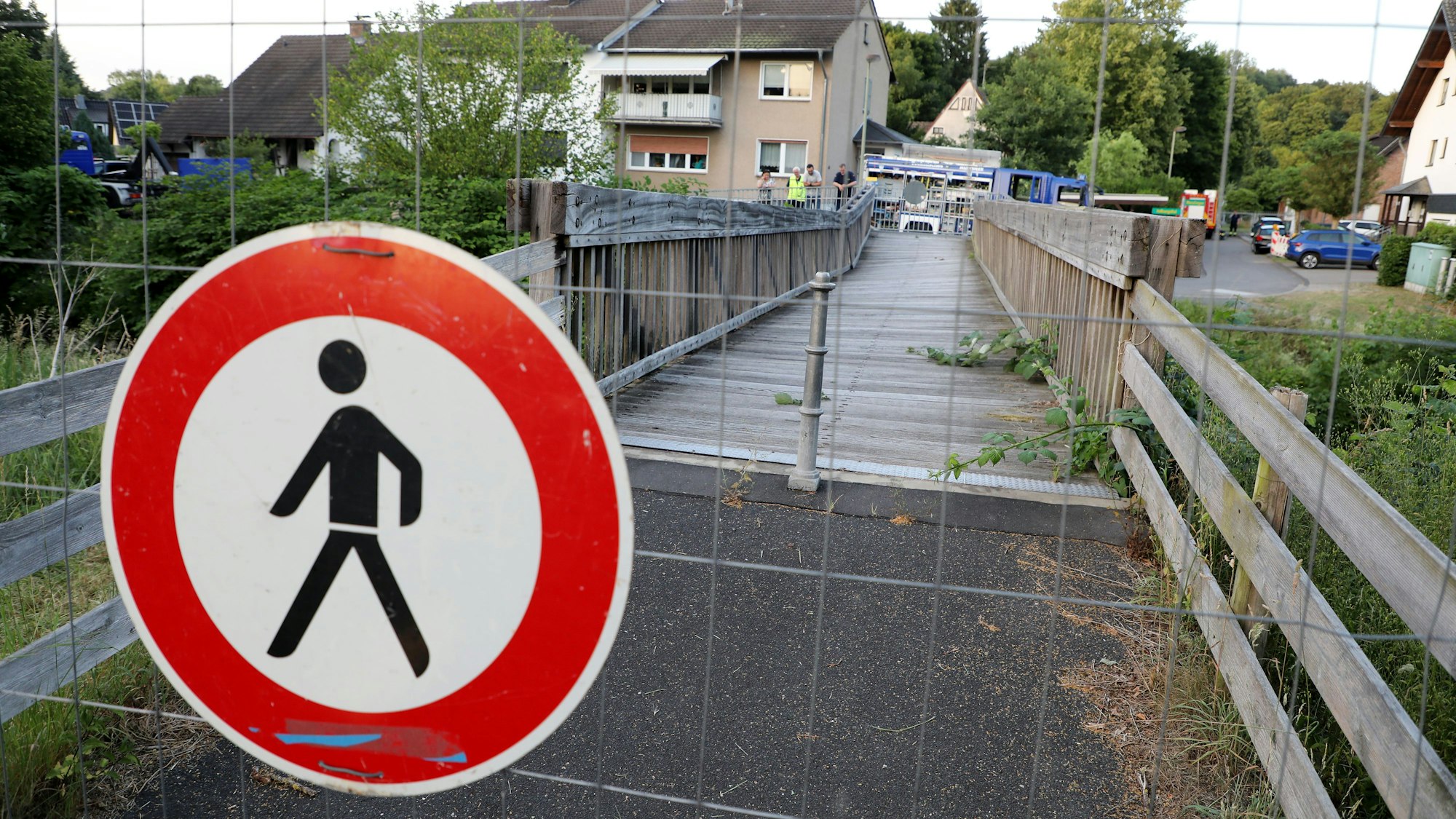 Ein Schild „Durchgang für Fußgänger verboten“ hängt an einem Bauzaun vor einer maroden Holzbrücke in Rösrath.