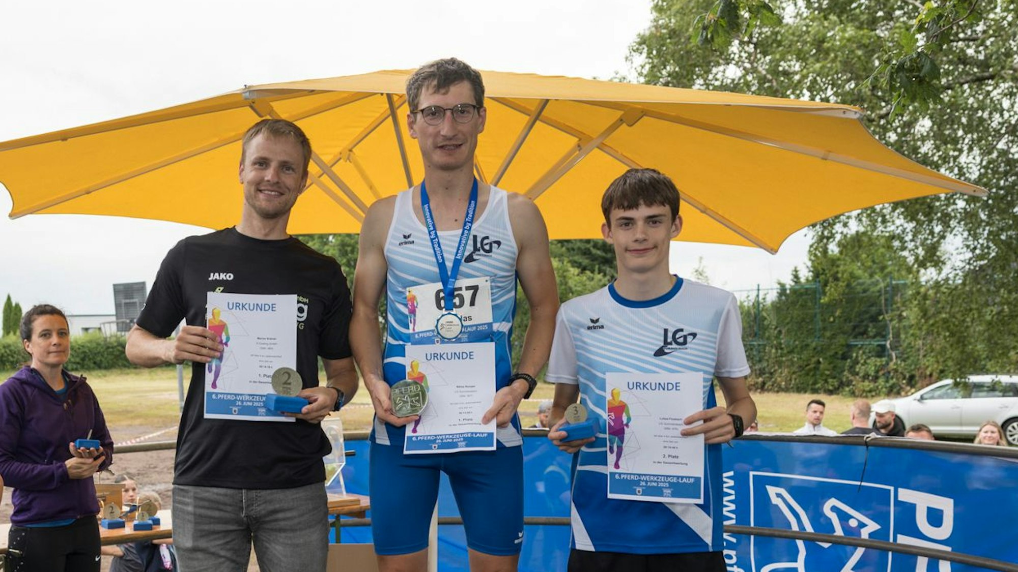 Drei Läufer stehen auf einem Siegerpodest.