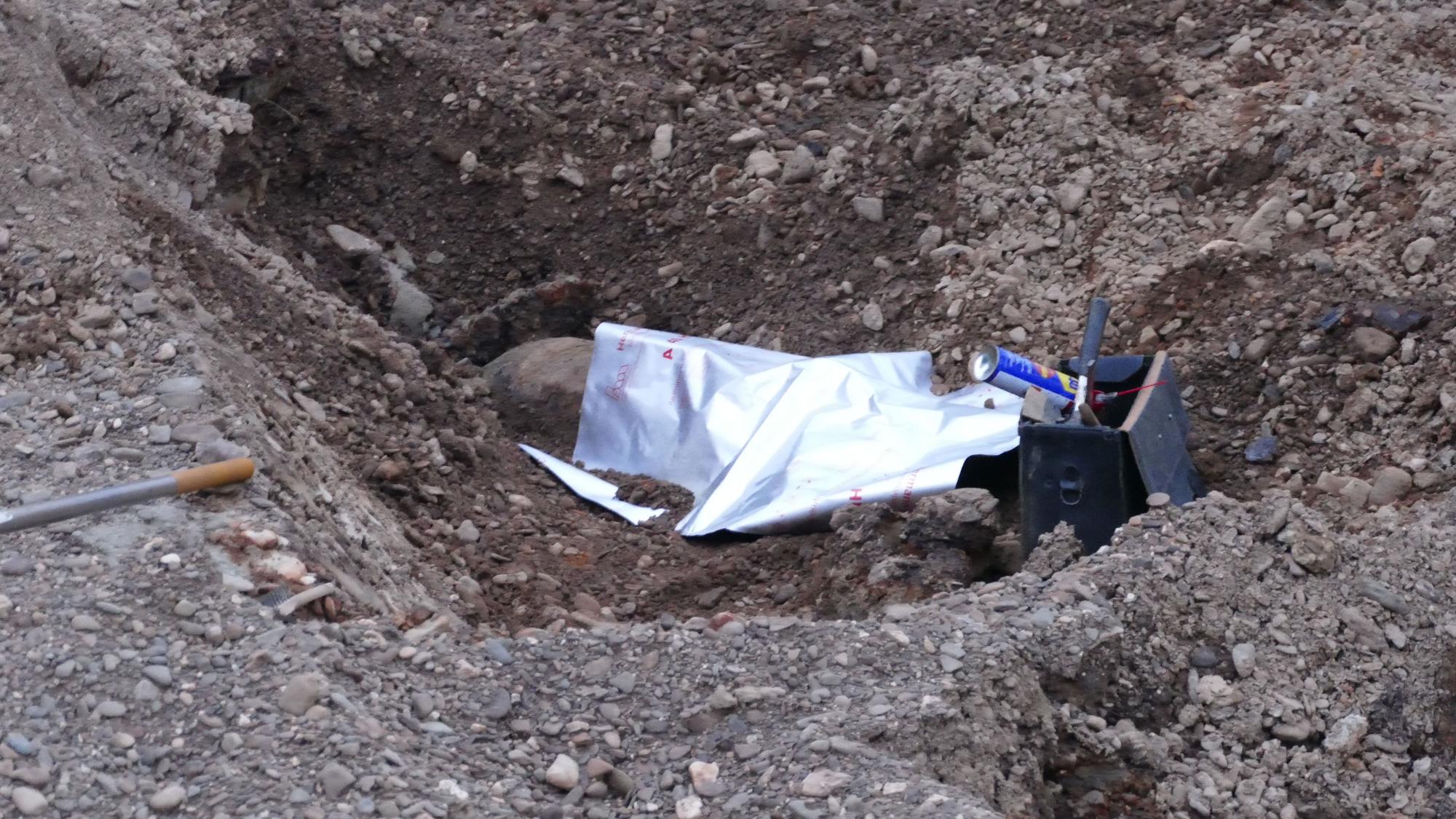Von einer Plane abgedeckt, liegt die Bombe in der Baugrube.