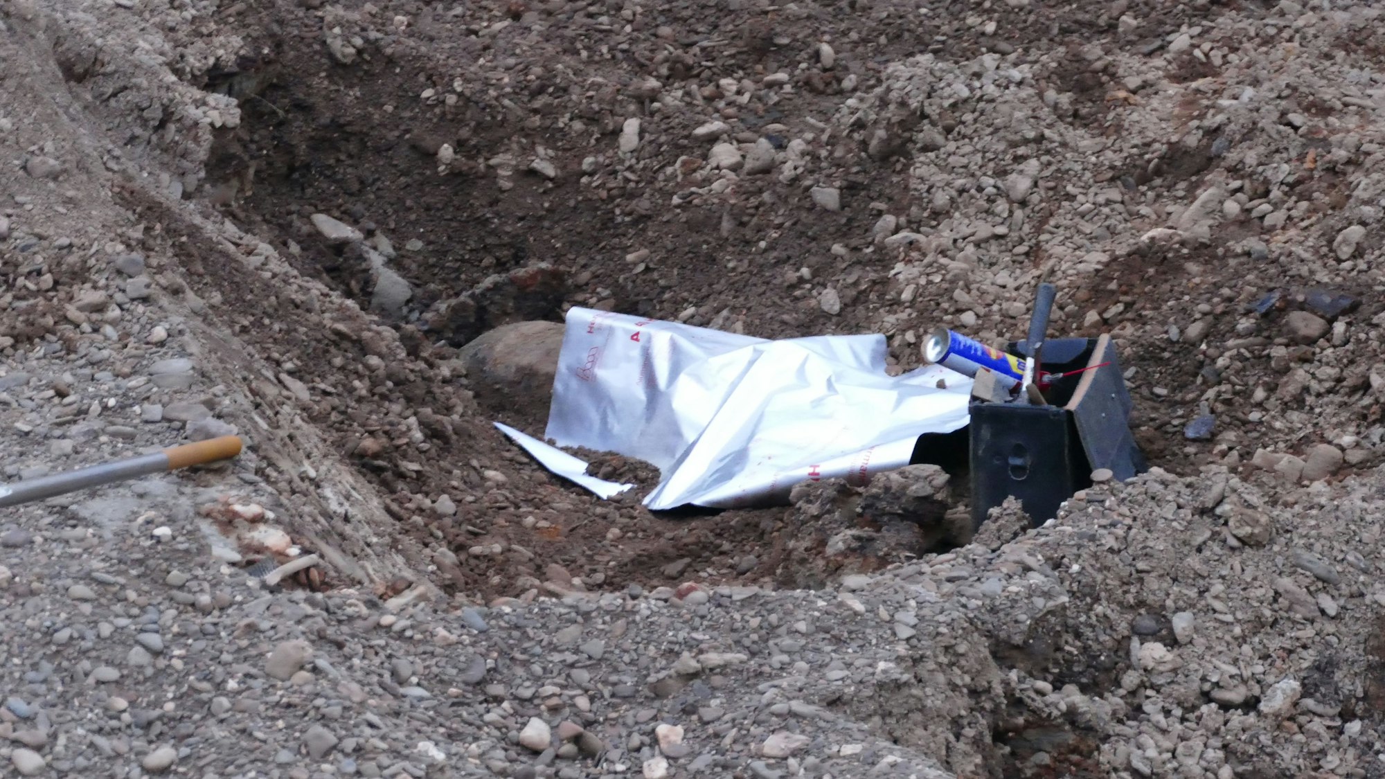 Von einer Plane abgedeckt, liegt die Bombe in der Baugrube.