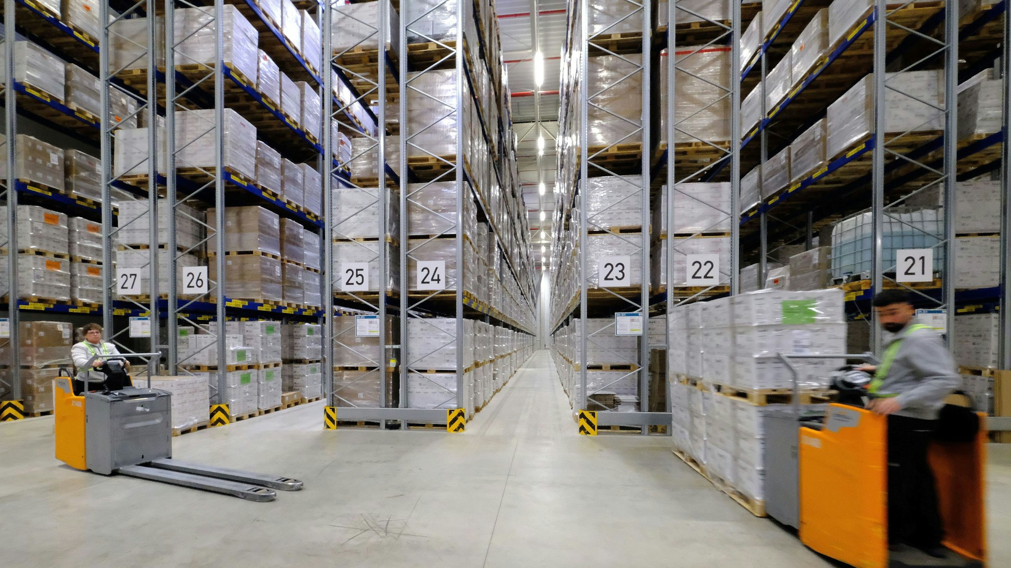 Blick in das Schmalganglager in der neuen Berners-Logistikhalle, im Vordergrund sind zwei Mitarbeiter mit Staplerfahrzeugen zu sehen.
