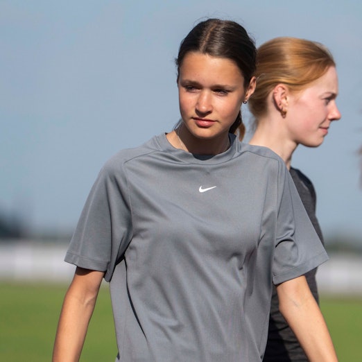 Zwei junge Sportlerinnen stehen hintereinander. Die vordere schaut nach links unten, die anderen nach rechts.