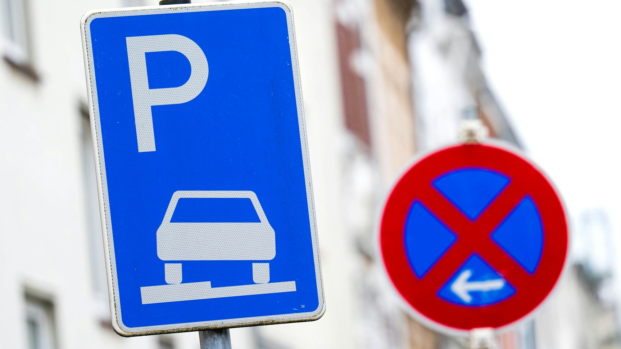 Ein Verkehrszeichen erlaubt das aufgesetzte Parken auf dem Gehweg, daneben steht ein Schild, das ein absolutes Halteverbot anzeigt