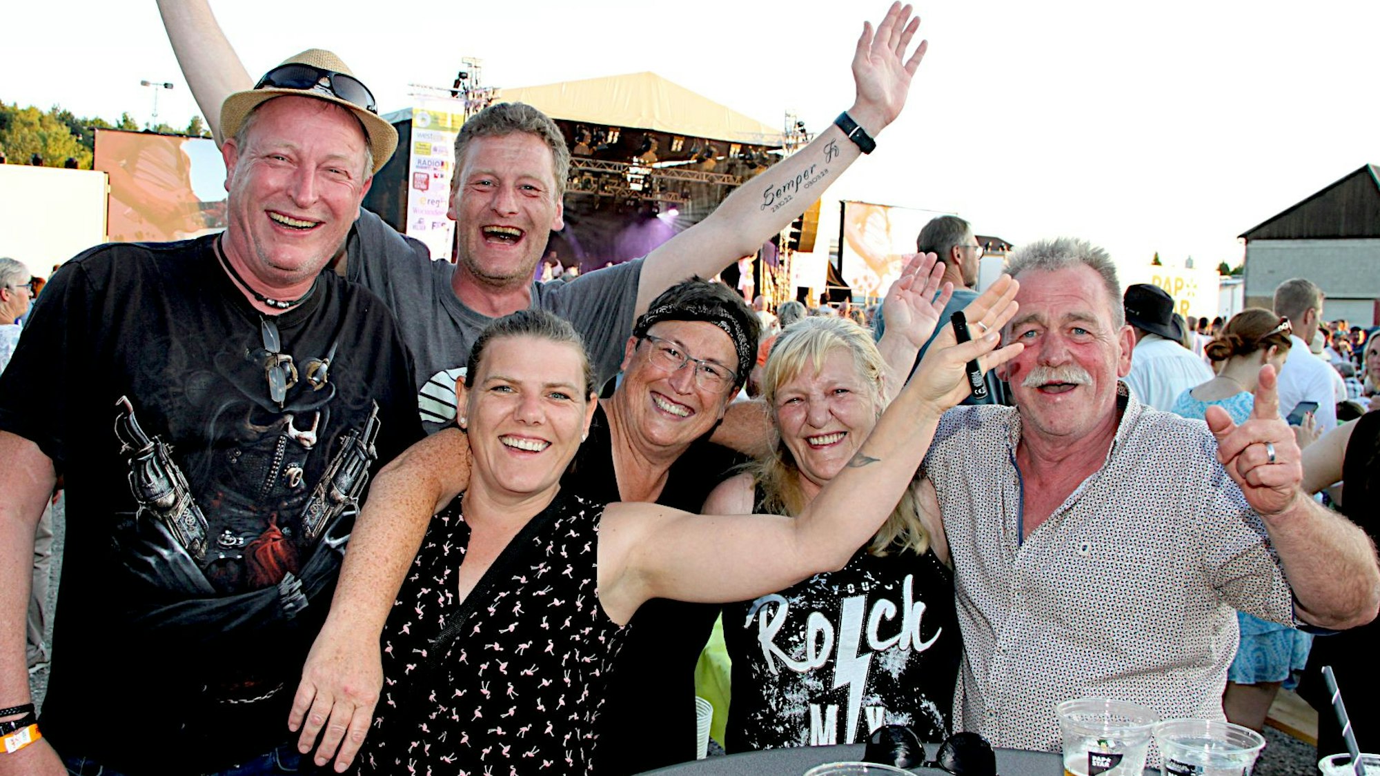 Mehrere Männer und Frauen feiern bei der Oldienacht und winken in die Kamera.