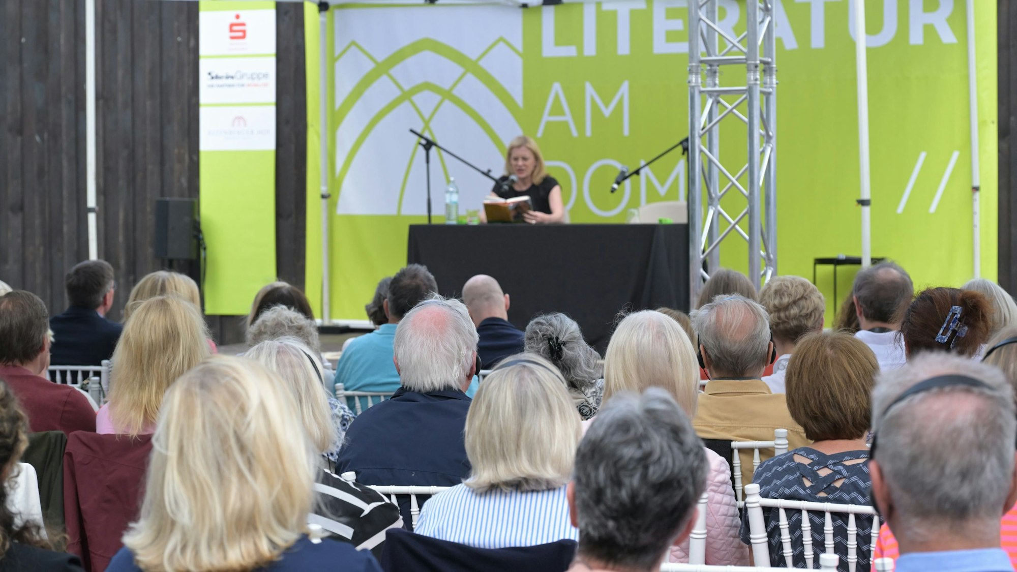 Caroline Peters liest auf einer Bühne vor Publikum aus ihrem Roman.