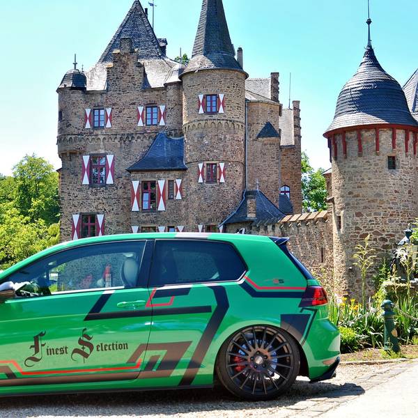 Ein grüner Tuning-Golf steht vor der Burg Satzvey
