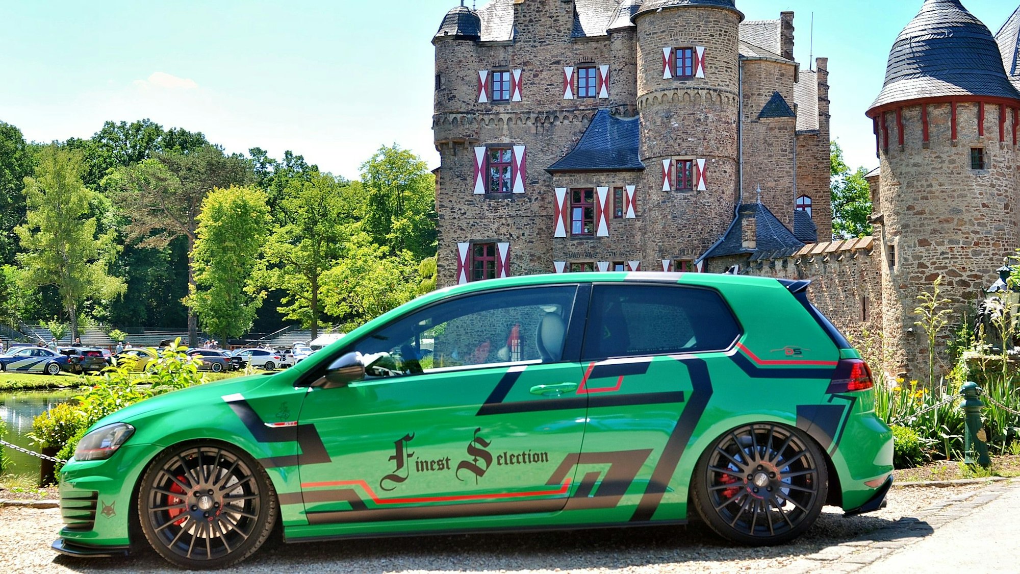 Ein grüner Tuning-Golf steht vor der Burg Satzvey