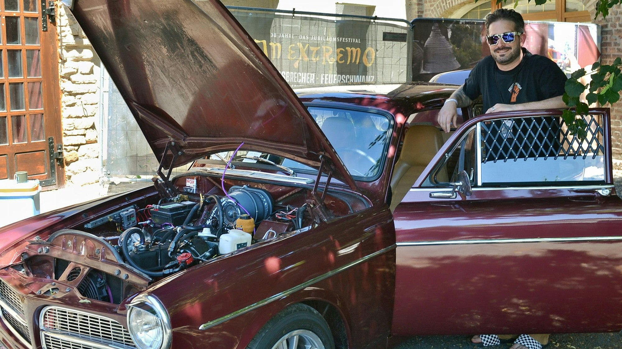 Jannis Kona steht an seinem Volvo Amazon. Die Motorhaube des Oldtimers ist geöffnet.