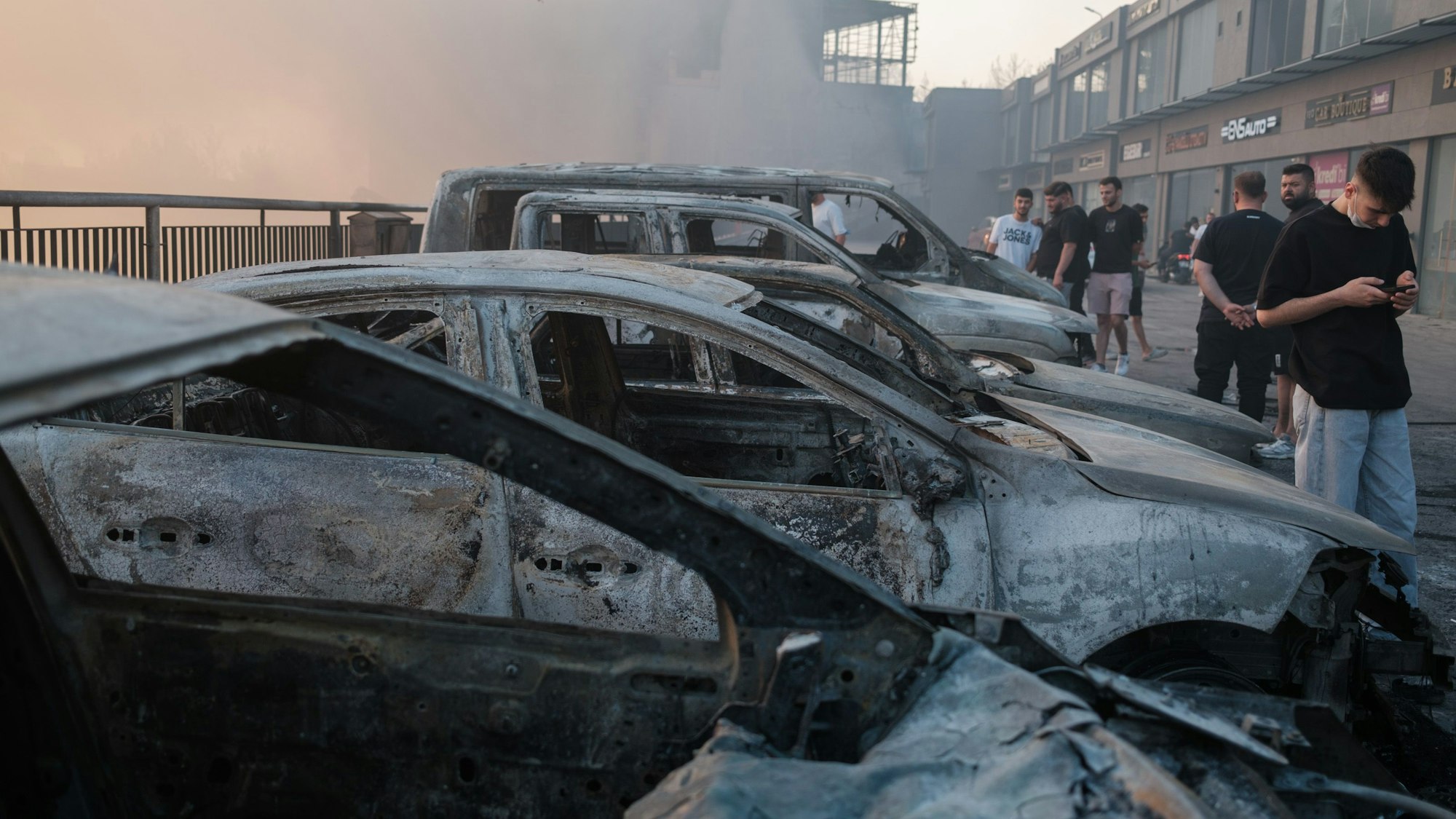 29.06.2025, Türkei, Izmir: Autos sind infolge eines Waldbrand zerstört worden. In der türkischen Provinz Izmir kämpfen Einsatzkräfte gegen sich mit starken Winden ausbreitende Brände.