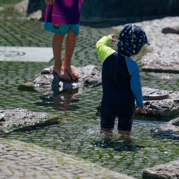 Seit Tagen wird es wärmer und wärmer in Köln: Kinder kühlen sich in einem Brunnen nahe des Rheins ab.