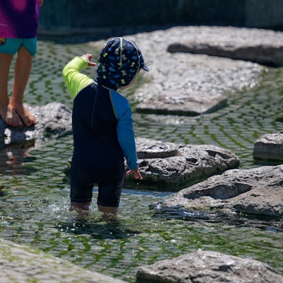 Seit Tagen wird es wärmer und wärmer in Köln: Kinder kühlen sich in einem Brunnen nahe des Rheins ab.