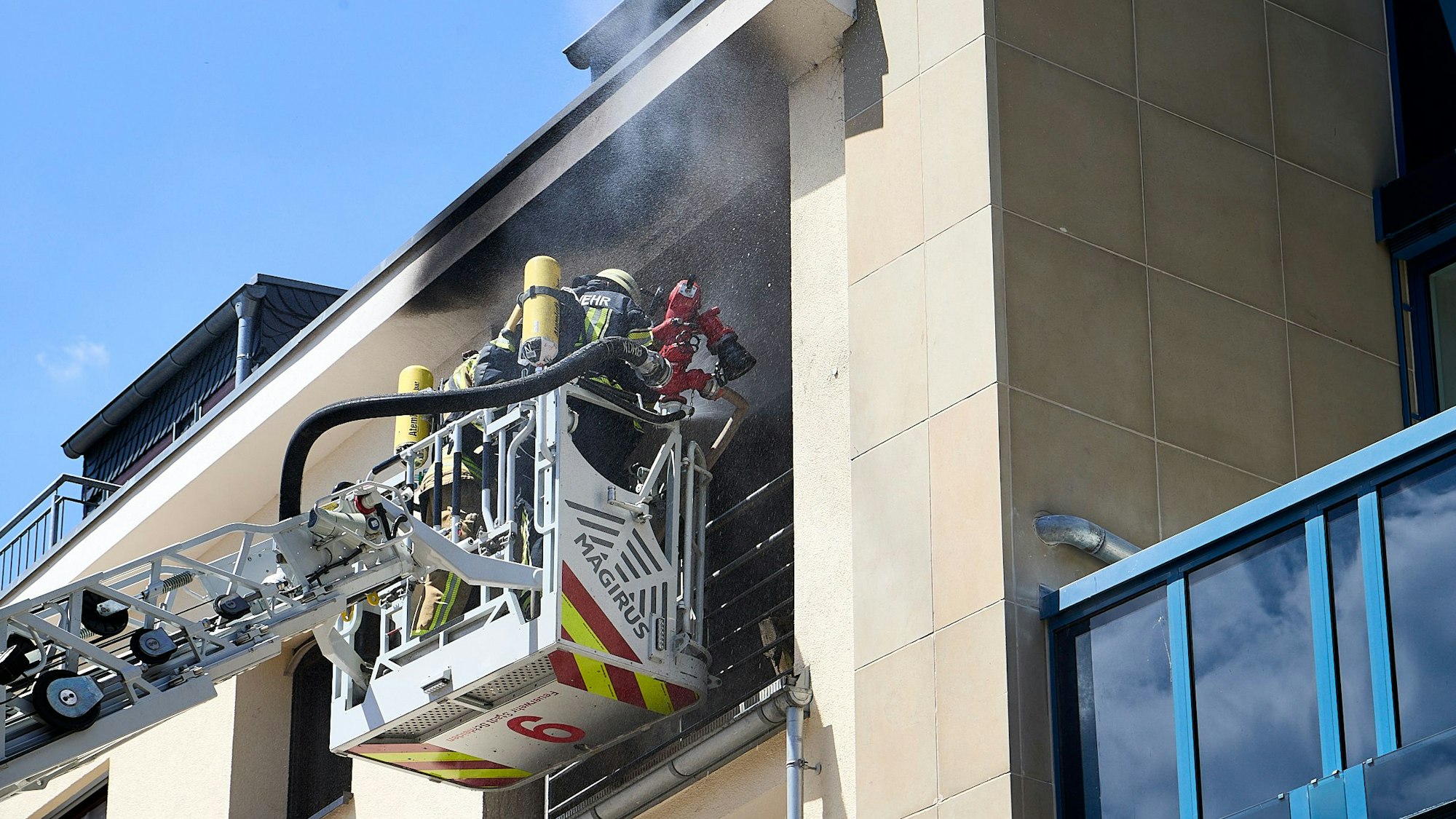 Das Foto zeigt Feuerwehrleute, die von dem Korb der Drehleiter aus das Feuer löschen.