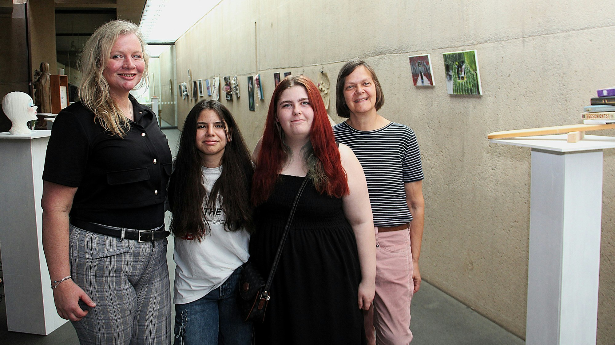 Zwei erwachsene Frauen stehen links und rechts von zwei Schülerinnen mit langen Haaren