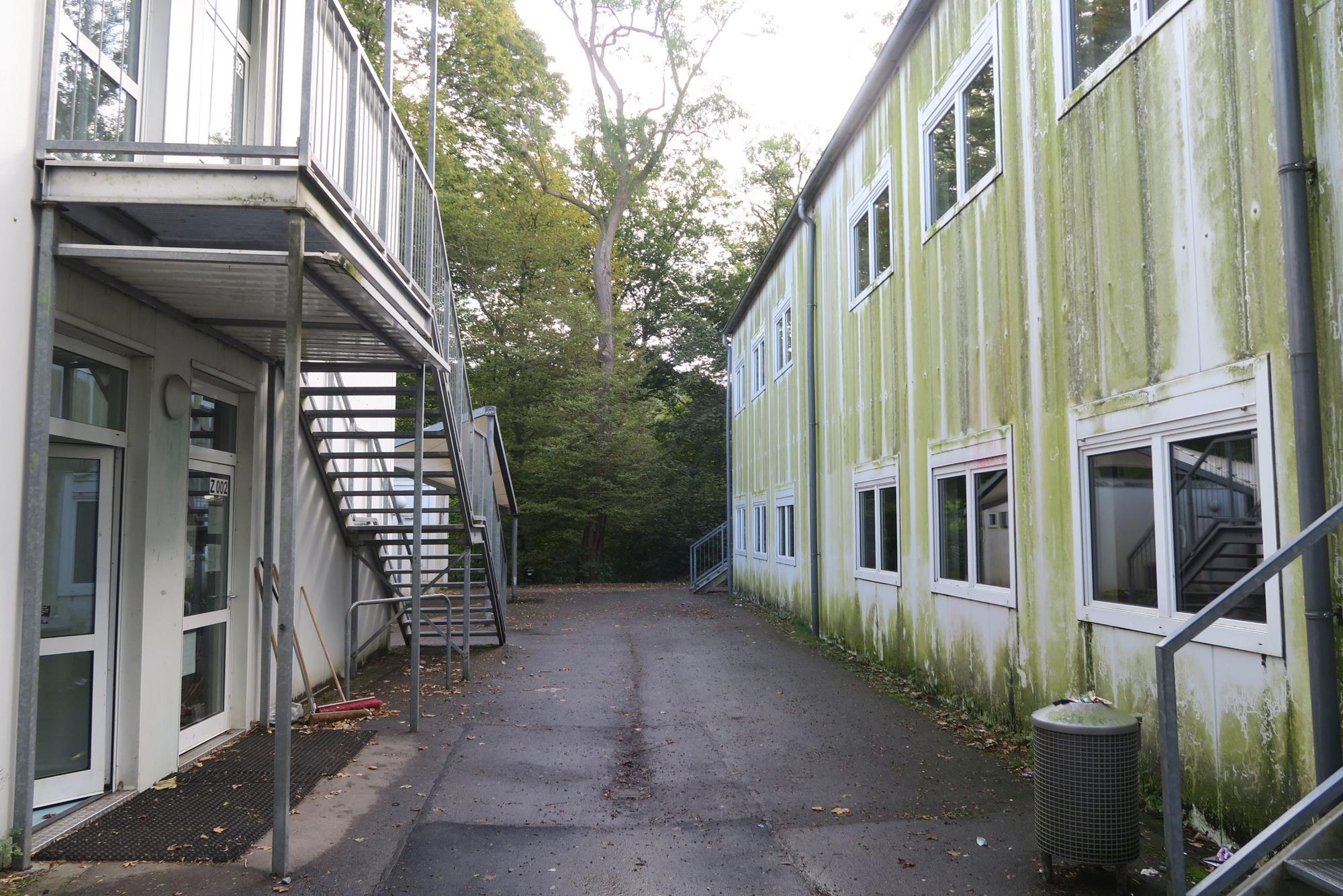 Zwei heruntergekommene Container-Bauten stehen nebeneinander.