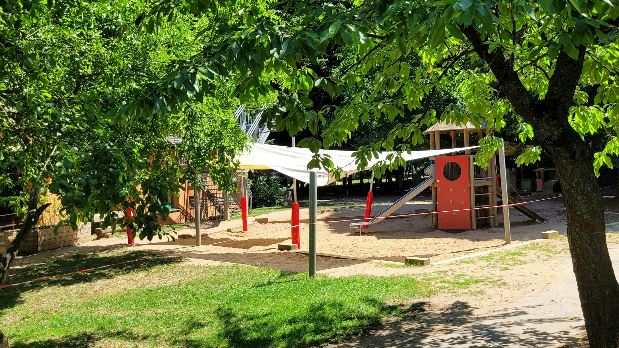 Auf dem Bild ist das Segel zu sehen, das Teile des Spielplatzes überdacht und so vor den Krähen schützt.