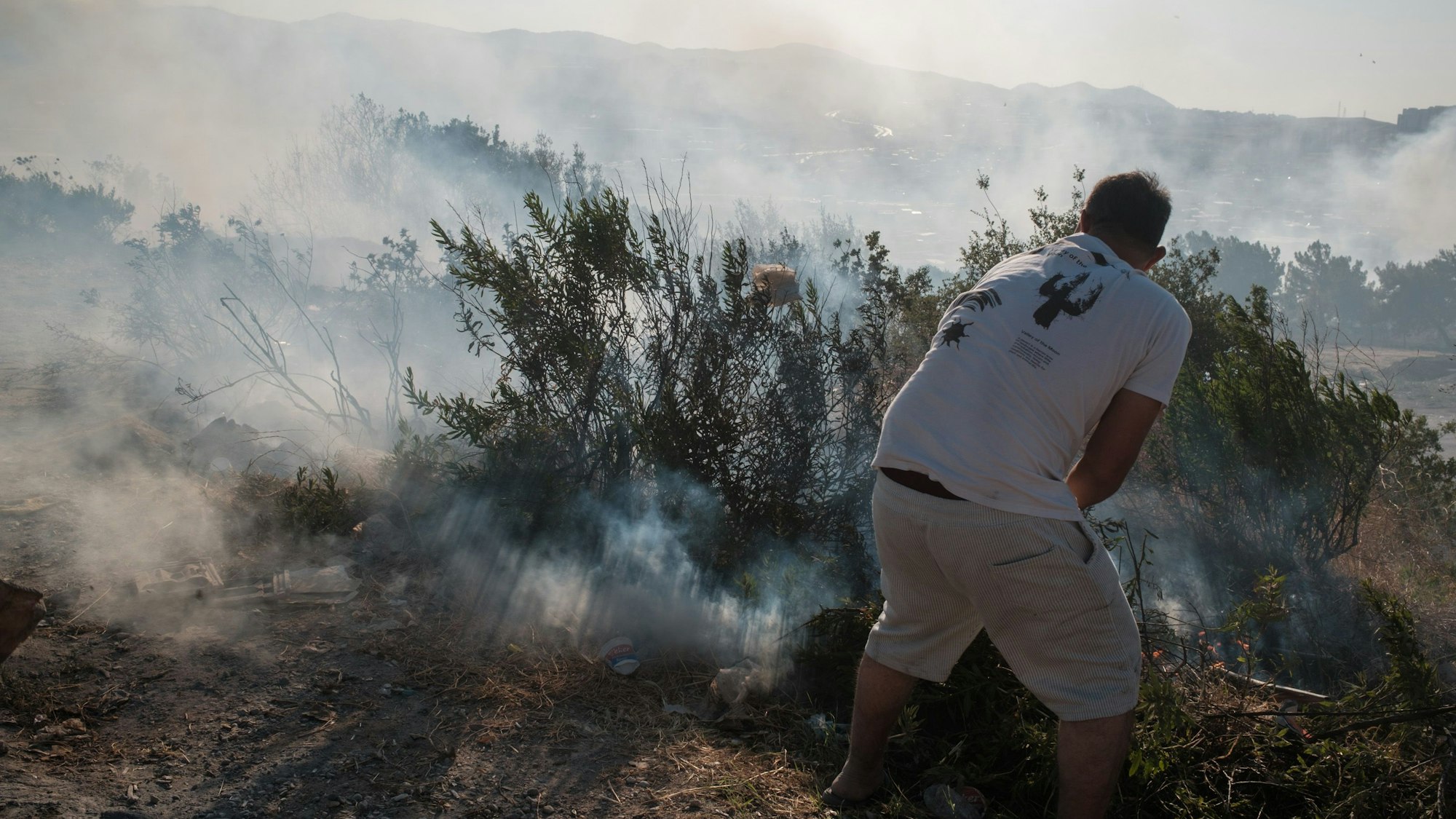 Ein Mann versucht Flammen bei einem Brand zu löschen. In vielen Teilen von Izmir sind Waldbrände ausgebrochen, die die Stadt in Rauch hüllen.