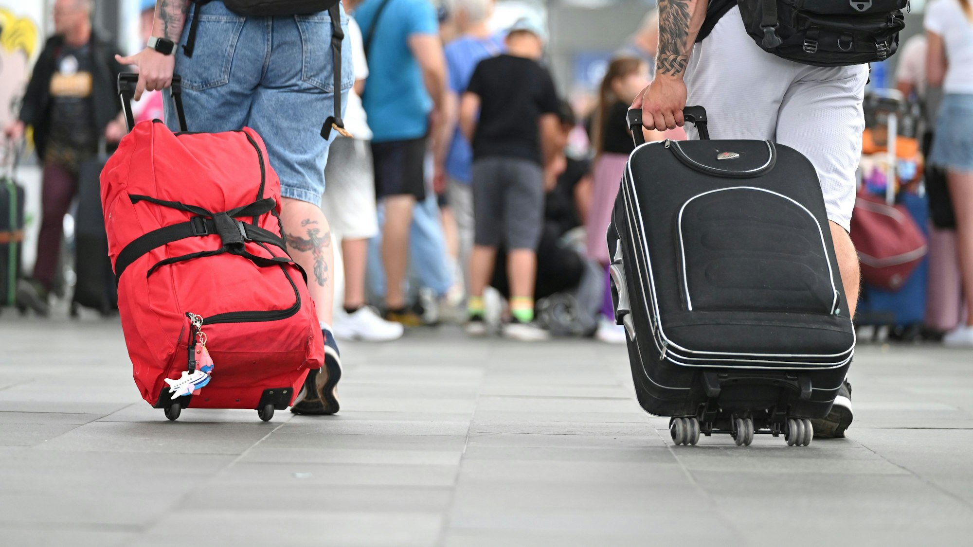 Flugreisende gehen mit Koffern durch den Flughafen Leipzig-Halle.