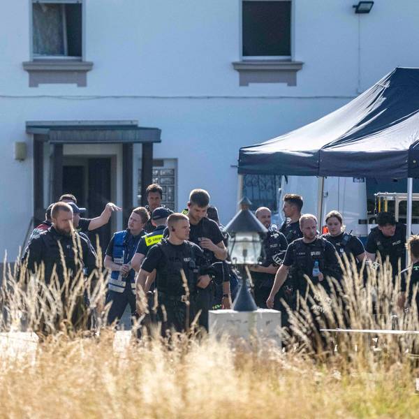 Das Bild zeigt einen Moment während der Razzia. Polizeibeamte und Mitarbeitende des THW befinden sich vor einem Haus.