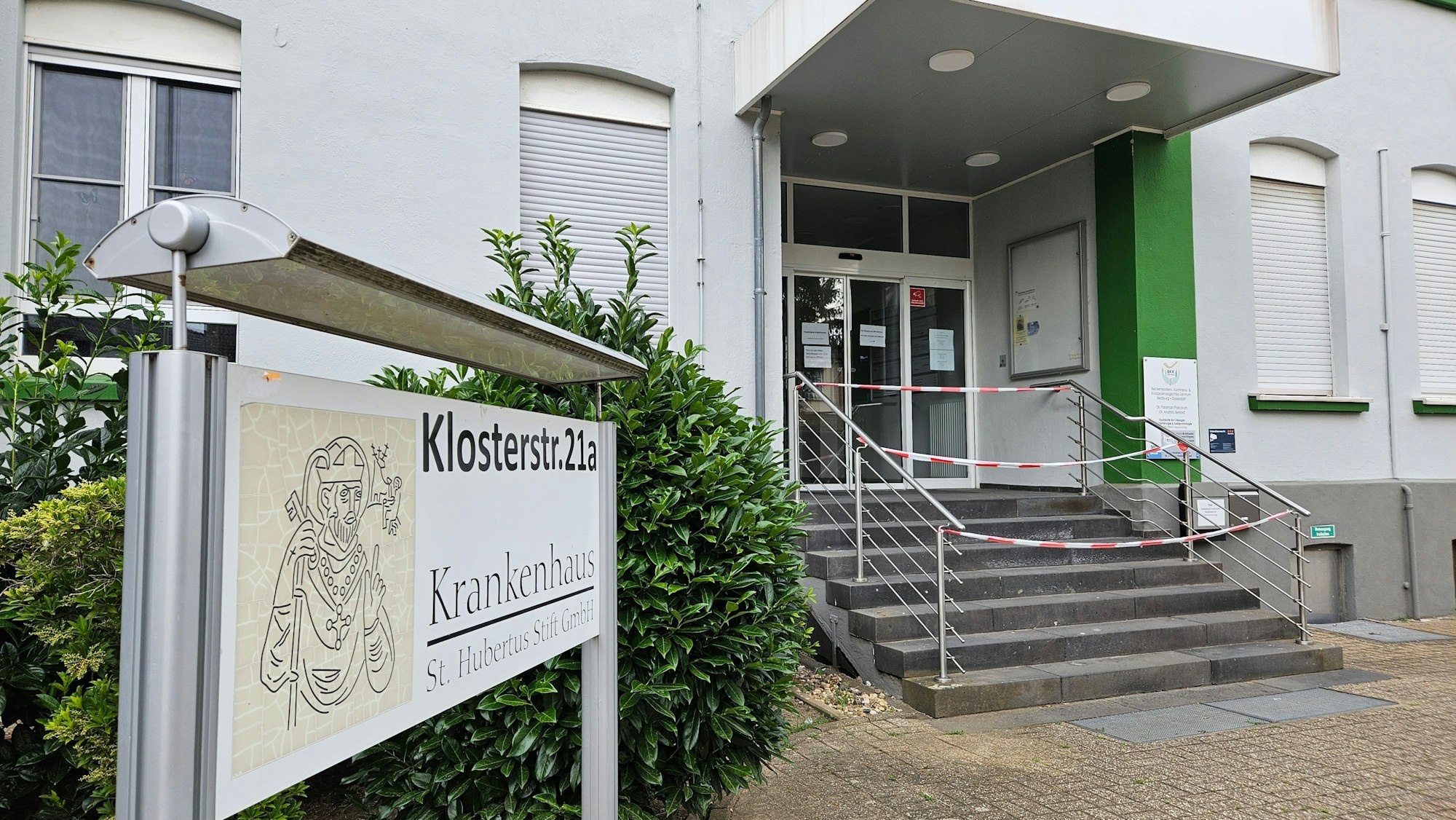 Das Bild zeigt den Eingang des Bedburger Krankenhauses. Es ist Absperrband vor der Eingangstreppe zu sehen.