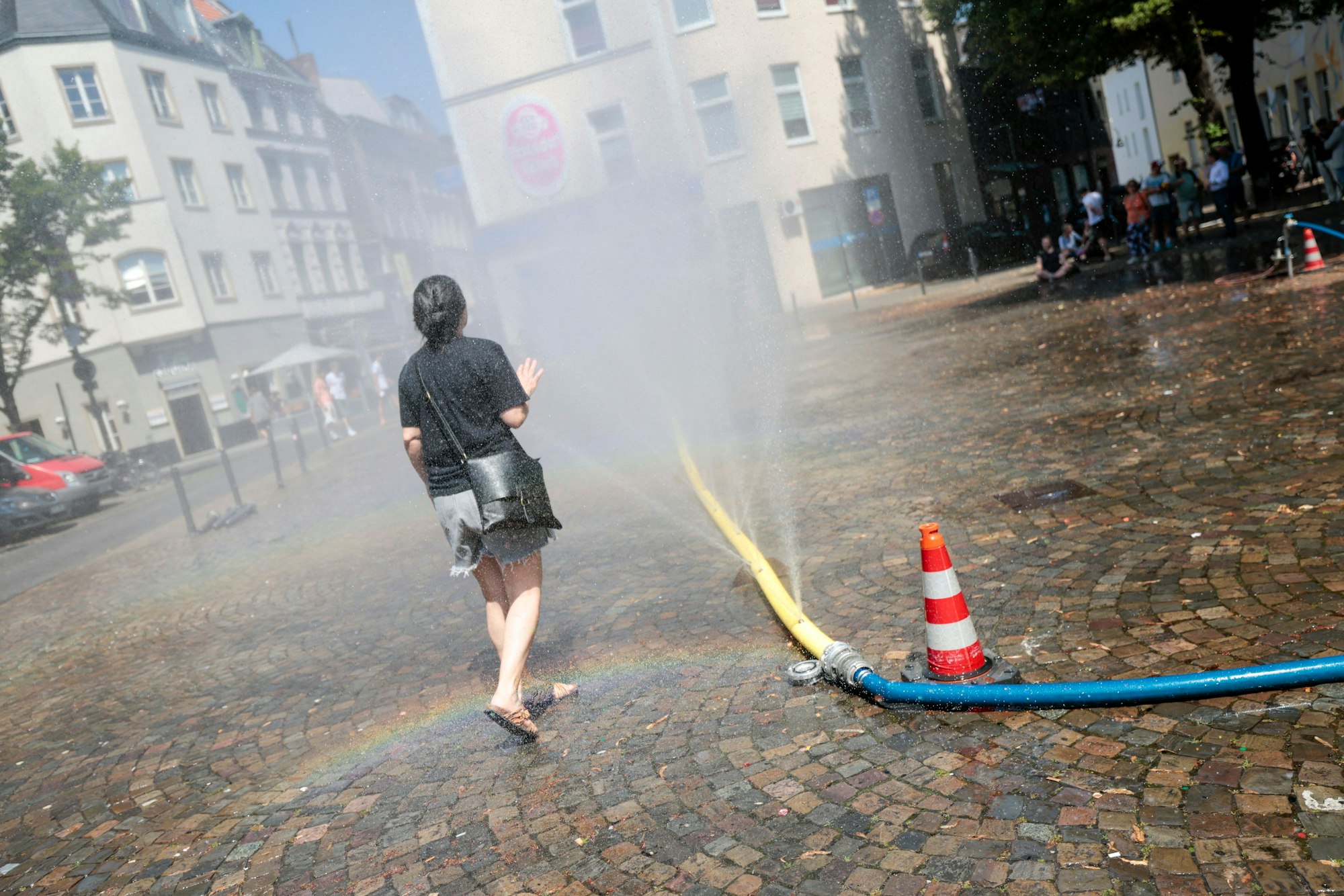Unter dem Motto „Cooling Cologne“ bietet die Stadt Köln in der Südstadt die Möglichkeit für eine Abkühlung mit Schläuchen an, die feinen Wassernebel versprühen.