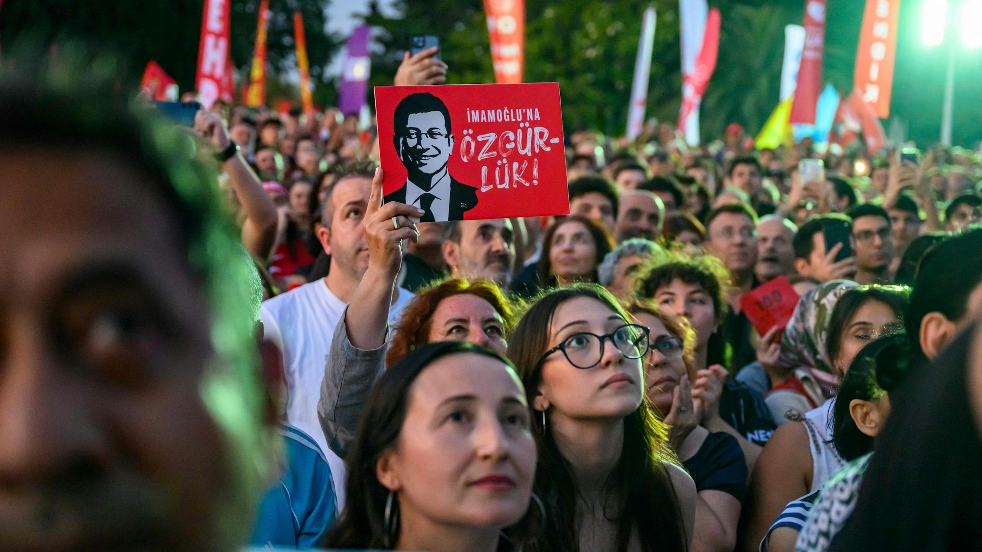 A protestor holds a placard of Istanbul's detained Mayor Ekrem Imamoglu as they listen to the leader of Turkey's main opposition Republican People's Party (CHP) Ozgur Ozel (not pictured) during a rally protesting the 100th day of his detention at the sarachane square in Istanbul on July 1, 2025. (Photo by Yasin AKGUL / AFP)